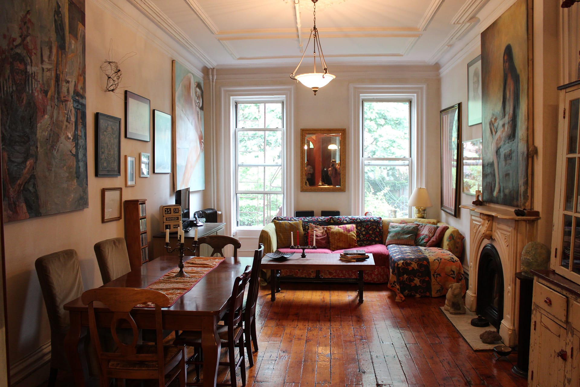 Parlor floor of a Cobble Hill townhouse before renovation with wood floors, dining area, and living room seating area.