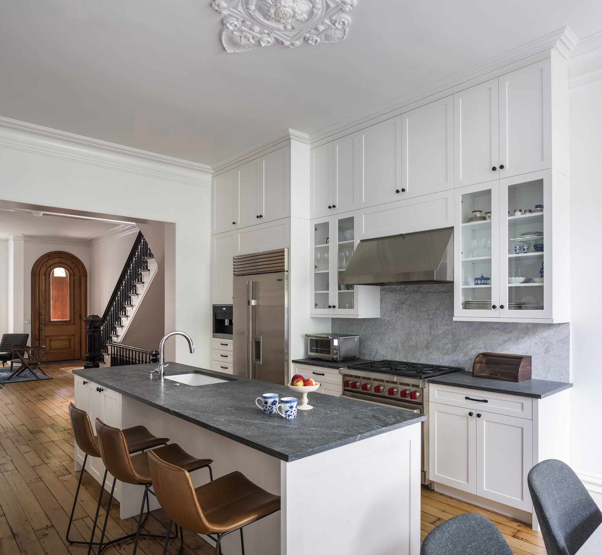 Renovated parlor floor of a Cobble Hill townhouse with natural wood floors and all-white walls and cabinetry.