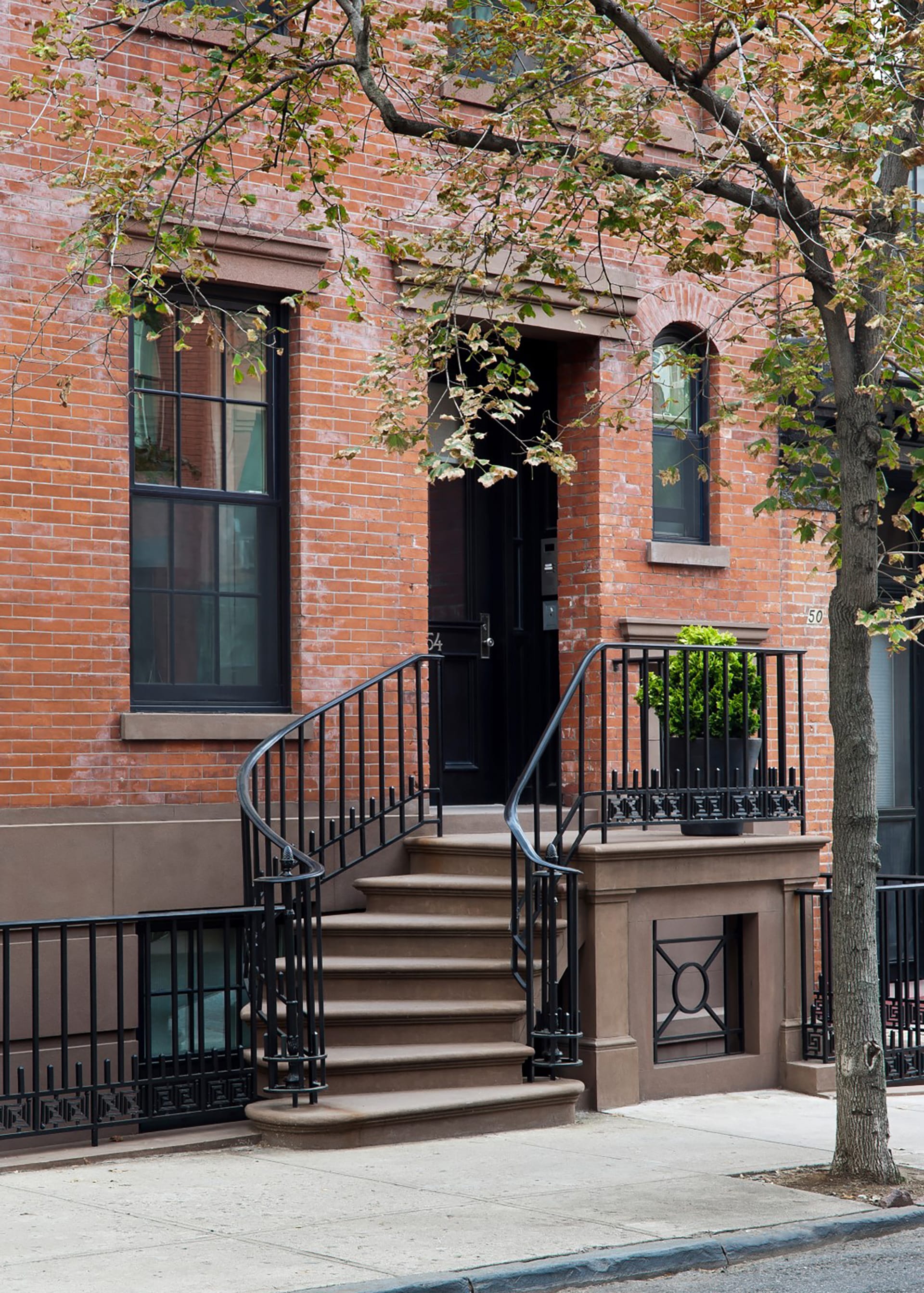 Front stoop of a Brooklyn Heights townhome. The stoop sits to the left of the front door, lined with black iron railings.