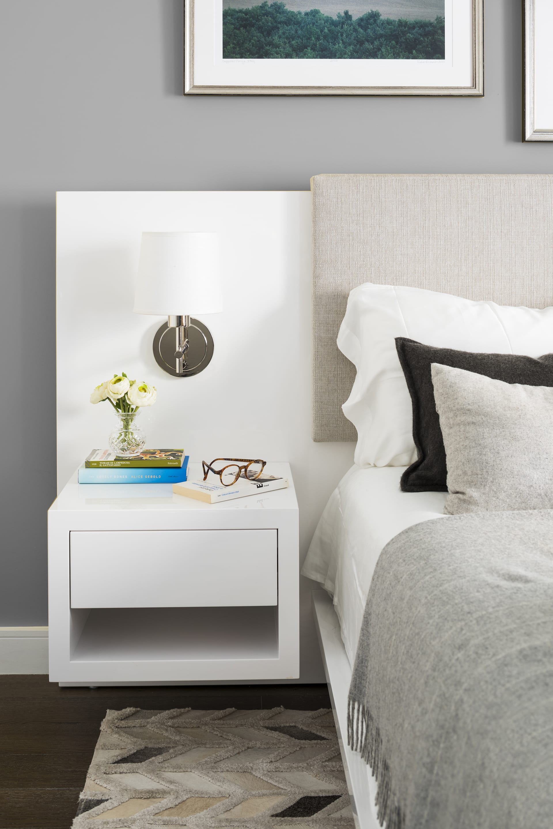 Floating white side table with a sconce next to the bed in a primary bedroom