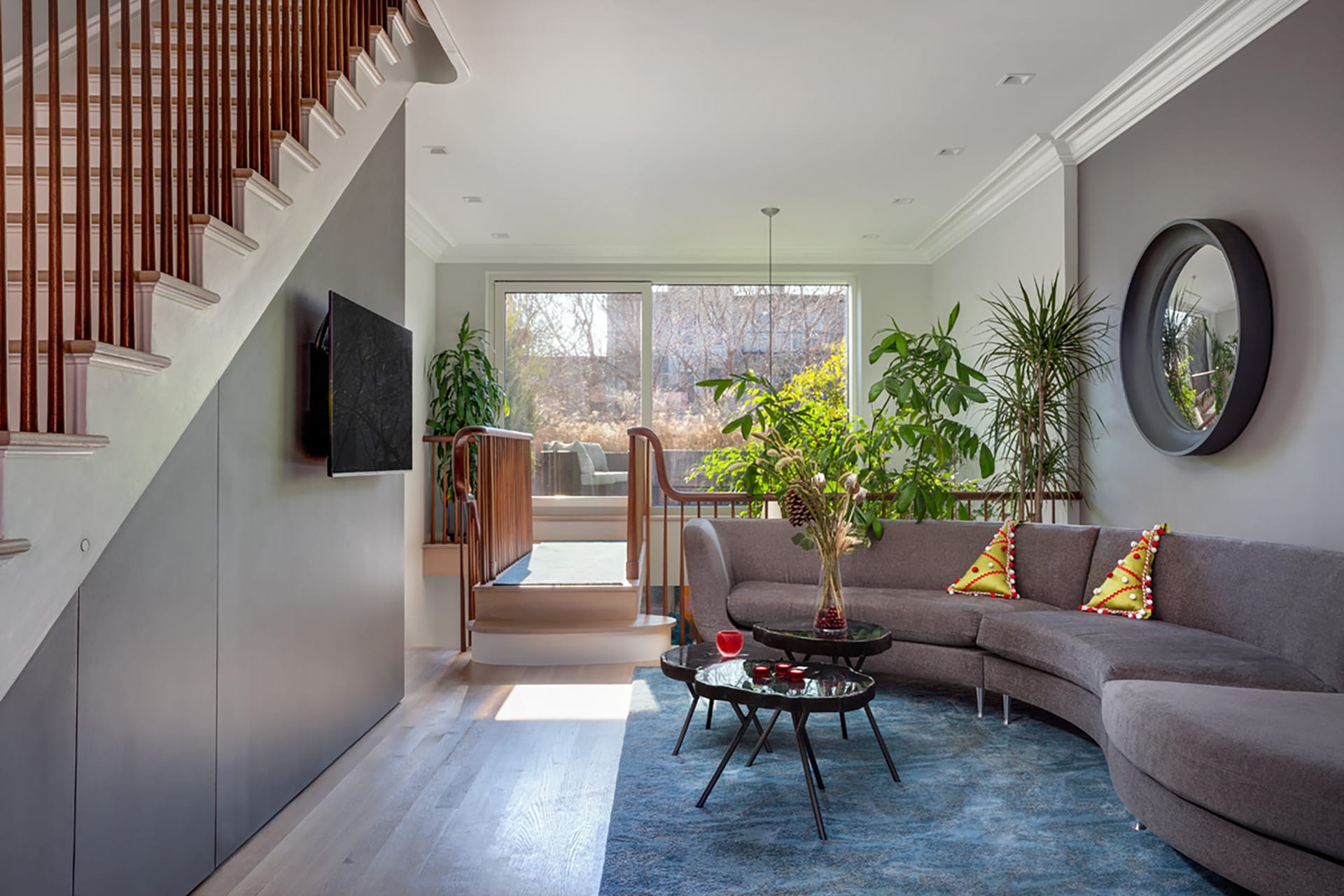 Second floor seating area with an asymmetric grey couch and walkway above a double-height space, leading to an elevated deck with Christmas decorations