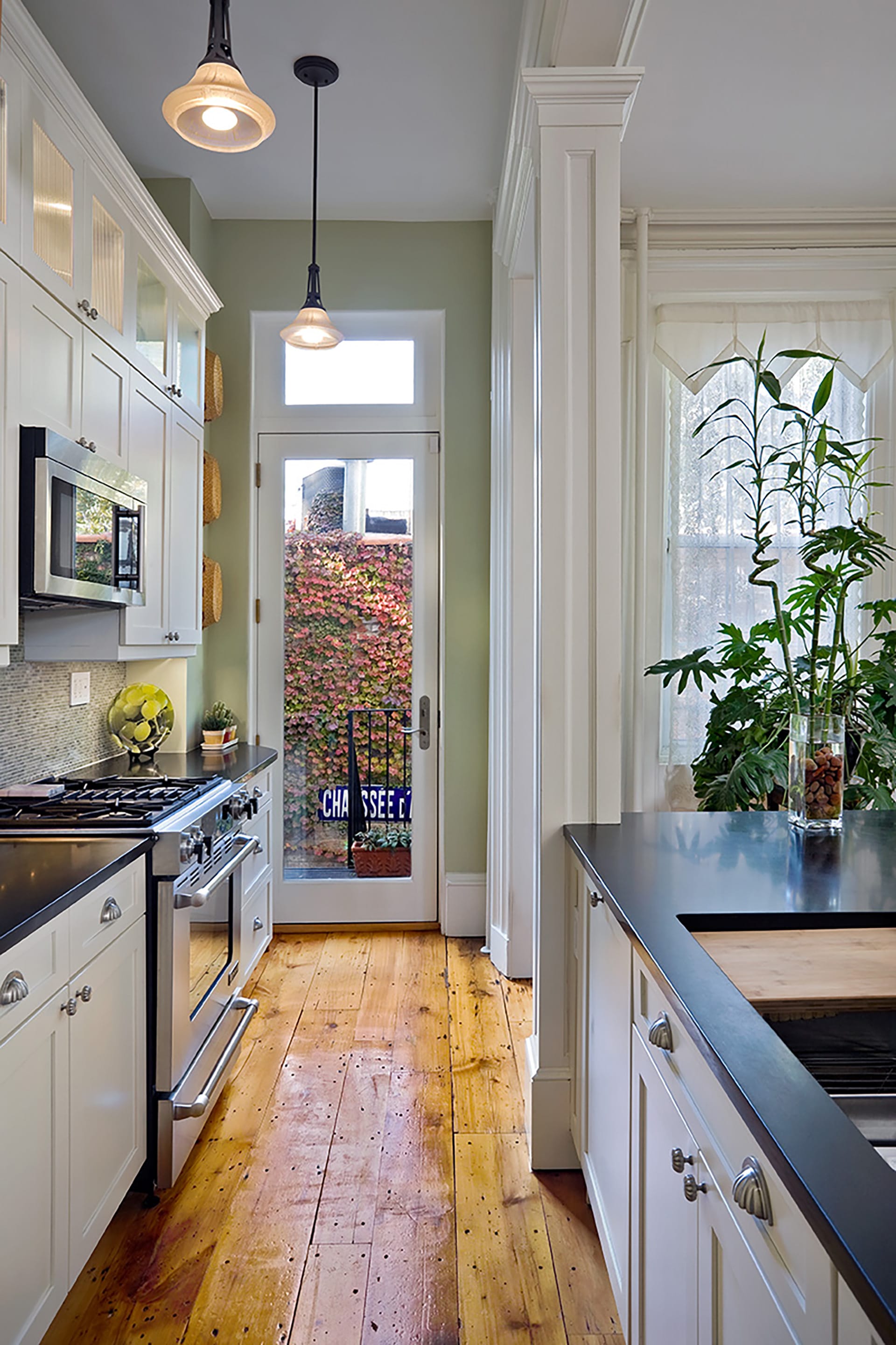 Kitchen with green walls, two pendant lights, and reclaimed wood floors.