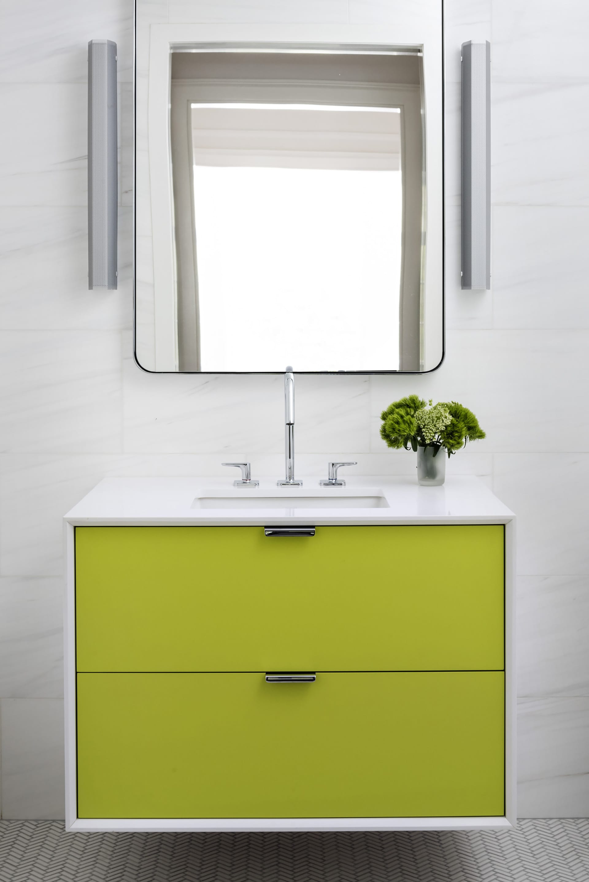 Floating vanity in an all-white bathroom with lime green drawers