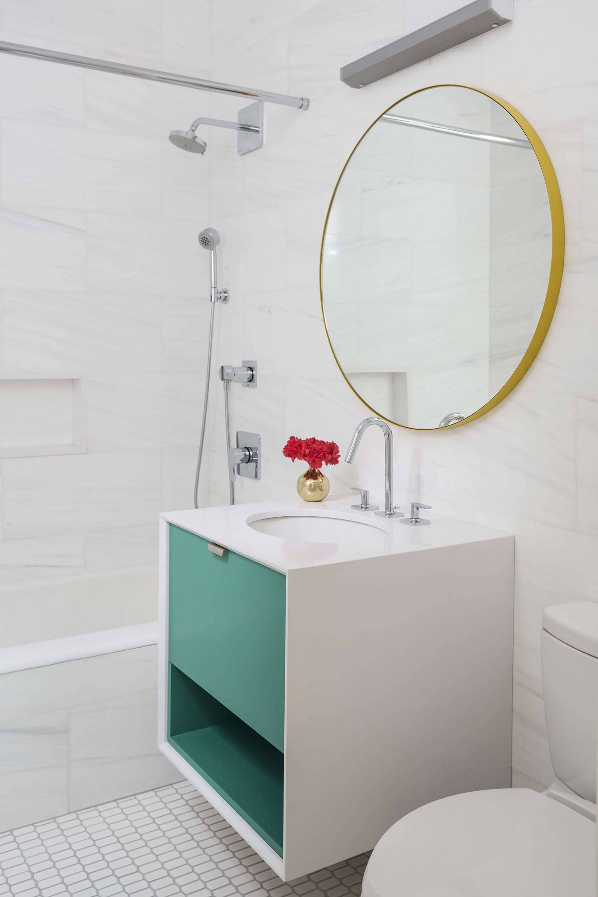 Floating vanity in an all-white bathroom with teal drawers