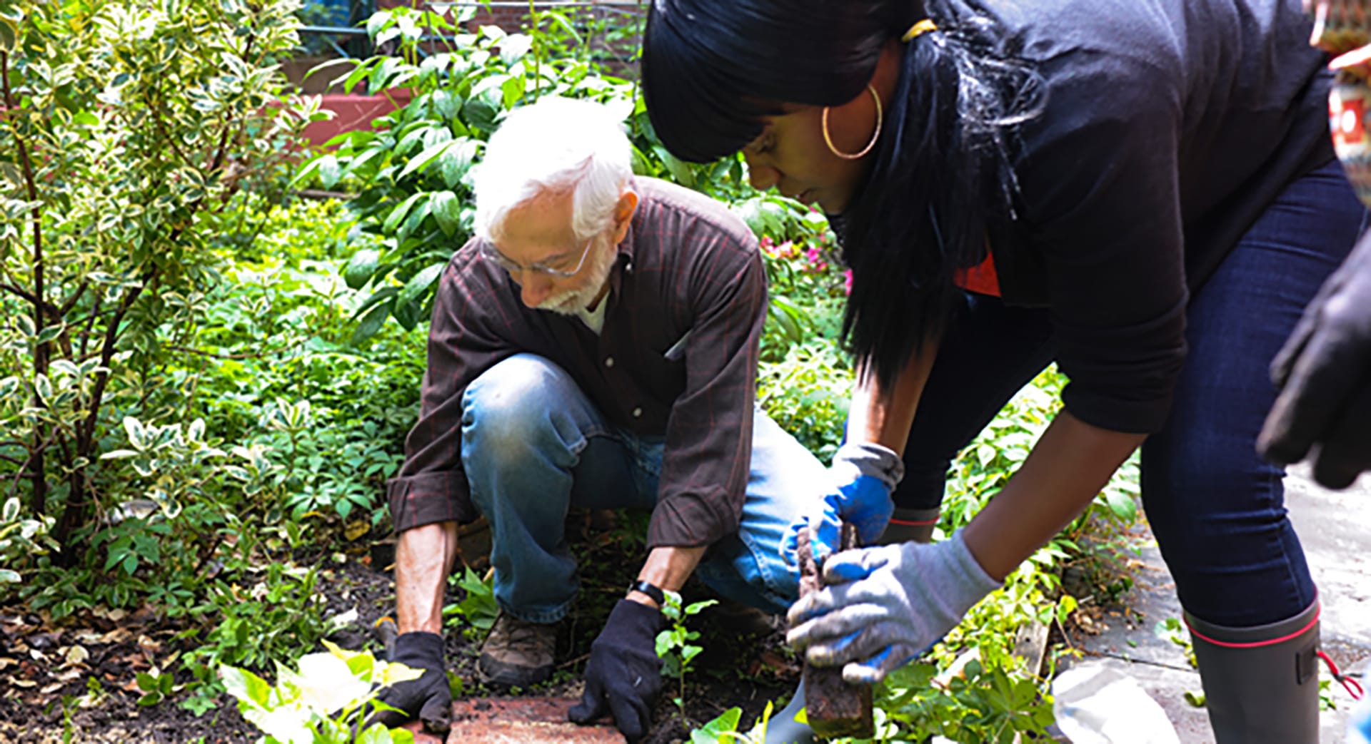 Ben Baxt places a paver in a garden with help from another volunteer.