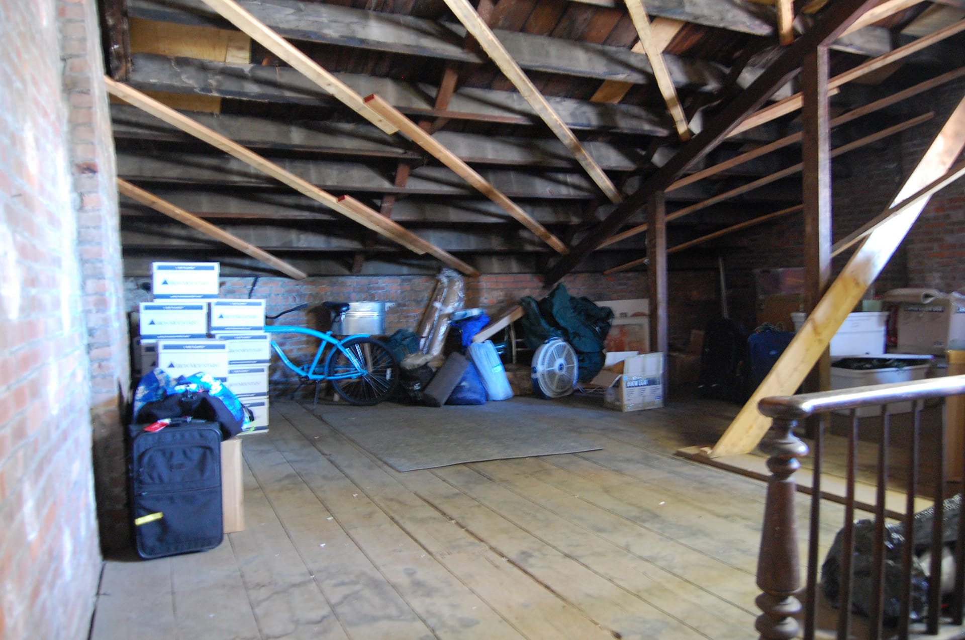 Attic of a Brooklyn Heights home before our renovation with wide plank wood floors and exposed ceiling beams.