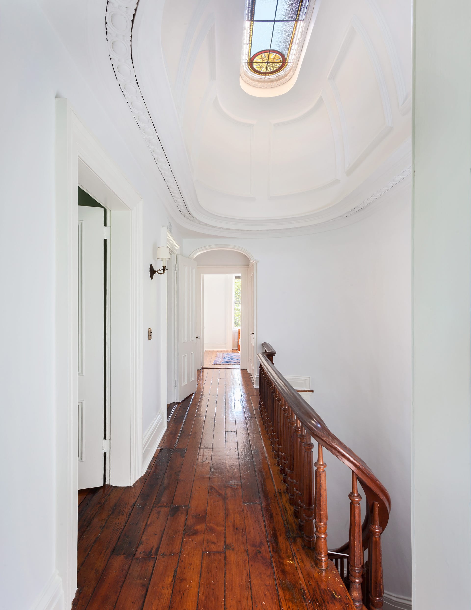 Upstairs hallway in a Brooklyn Heights home with a restored skylight, white walls, and dark wood floors