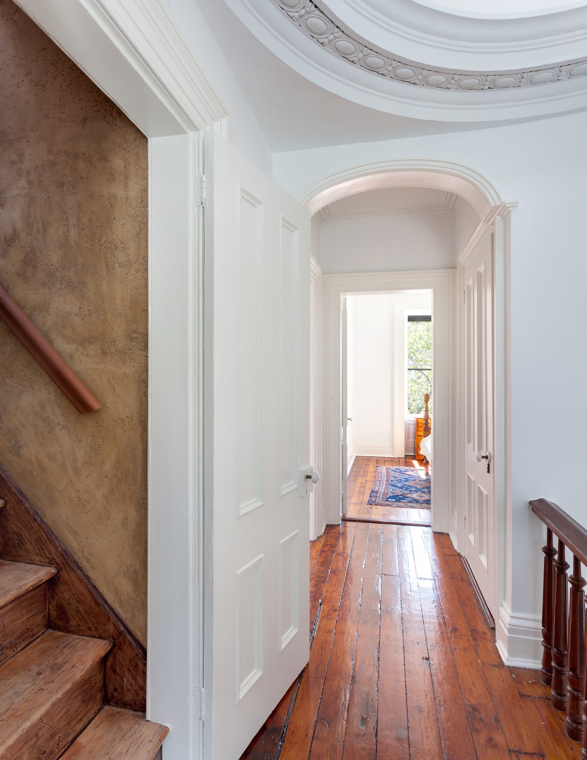 Upstairs hallway in a Brooklyn Heights home with a restored skylight, white walls, and dark wood floors