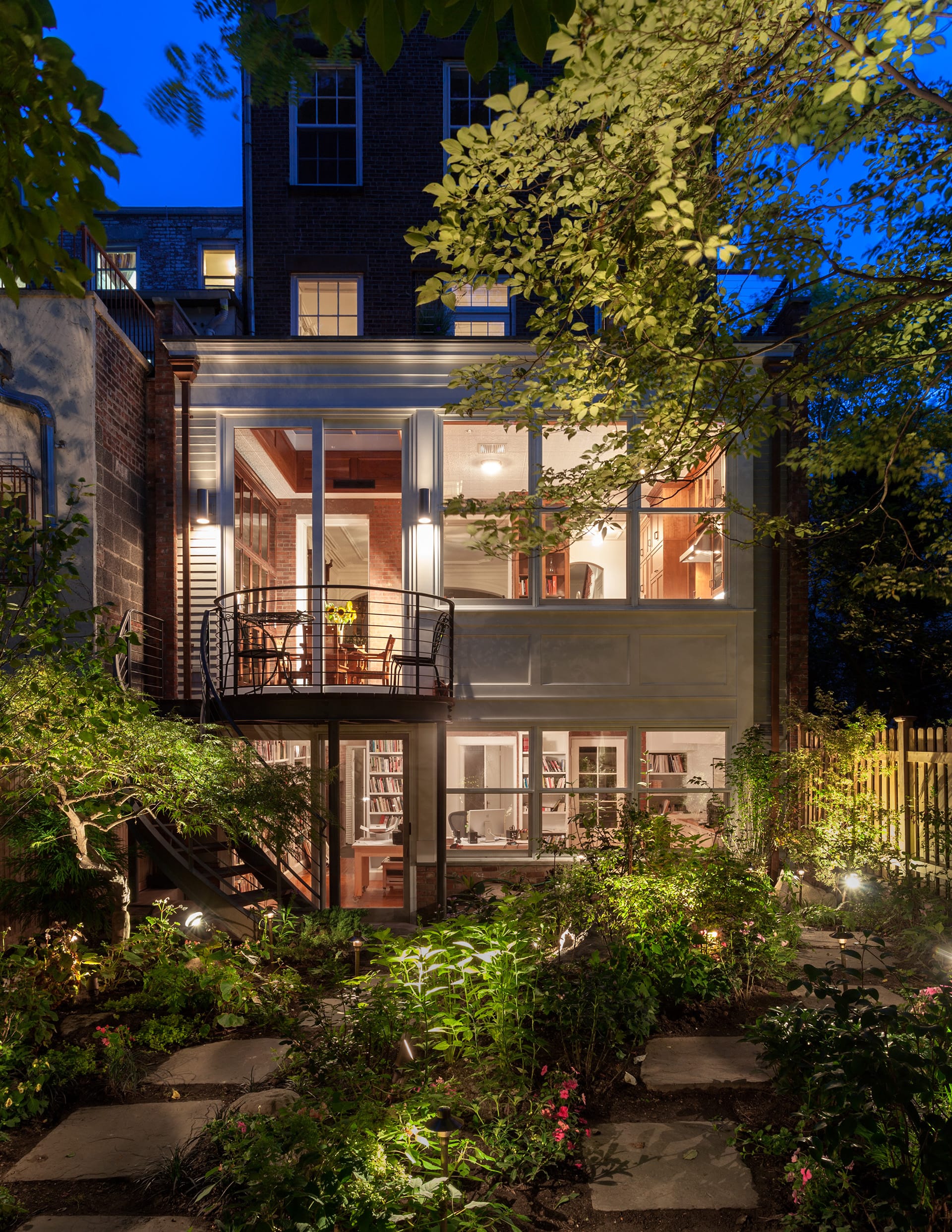 Rear facade after renovation with a newly landscaped rear garden, patio, and new larger windows