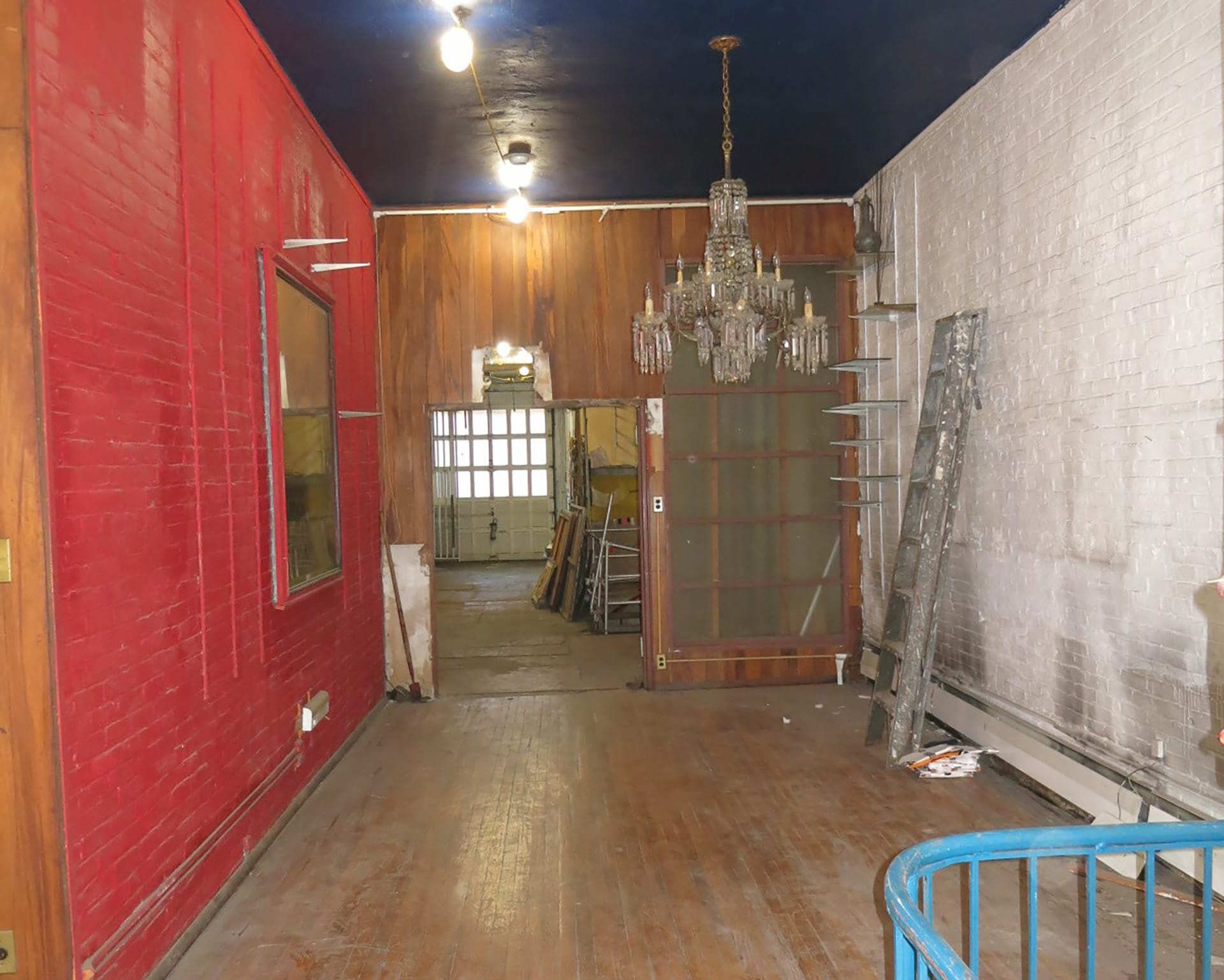 First floor of a Brooklyn Heights carriage house with painted exposed brick walls, dark blue ceilings, and narrow plank wood floors.