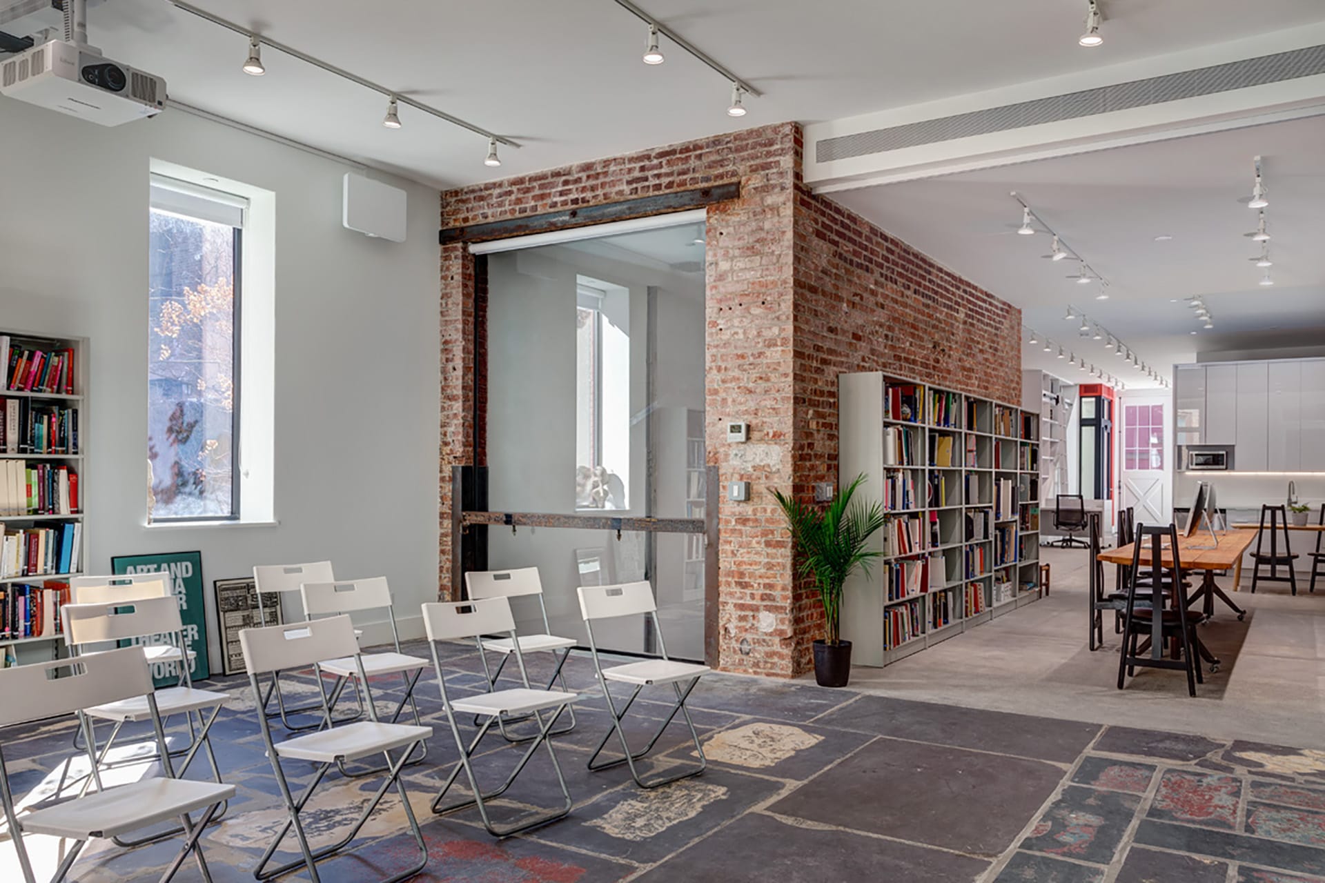 Meeting space with restored stone floors, bookshelves housing Asian Art History books, and an exposed brick elevator shaft converted into a stairwell.
