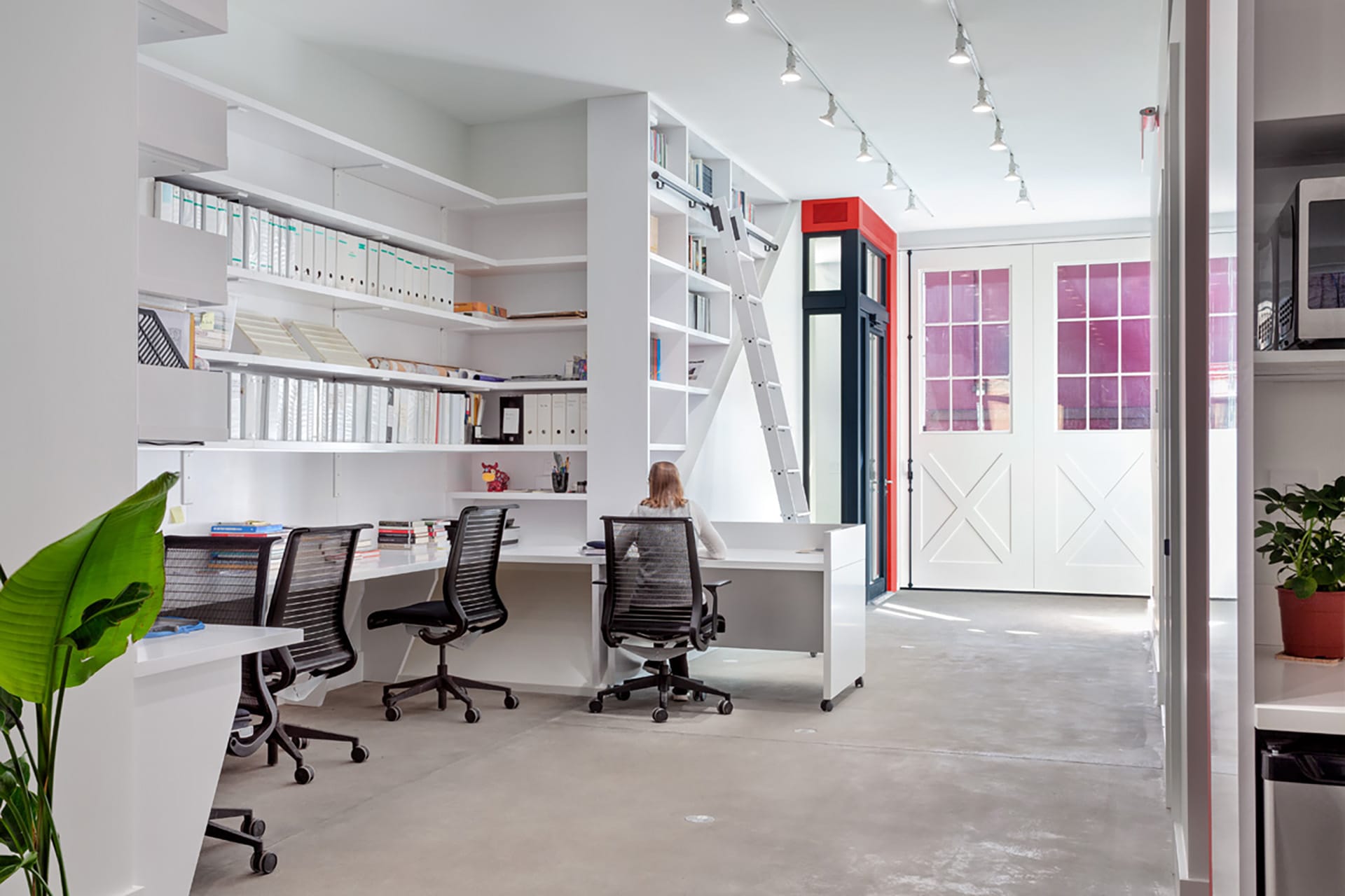 All-white office space of the Asia Art Archives with cement floors and red-and-black entry door