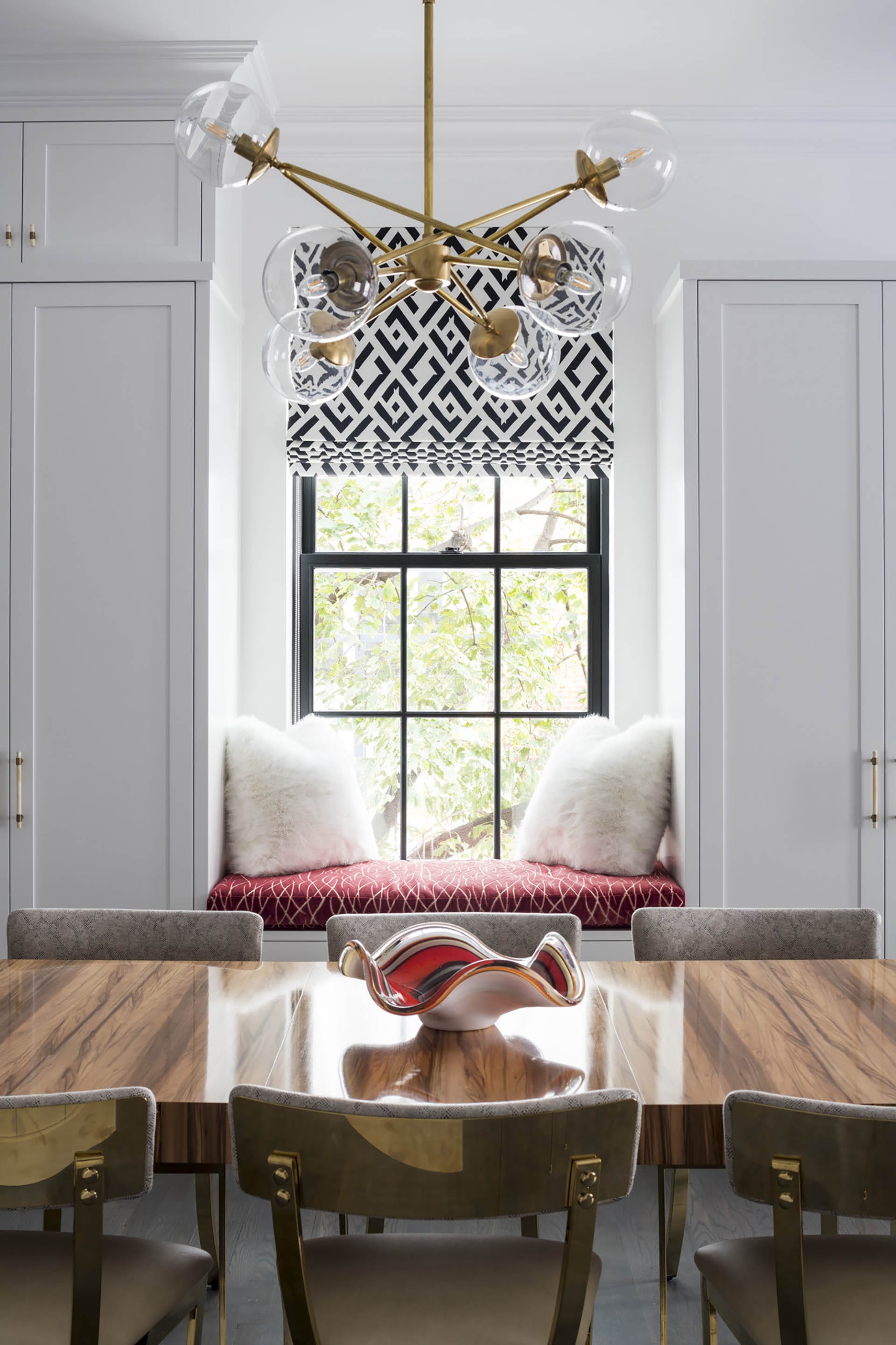 Brooklyn Heights dining room with a wood table, klismos chairs, a gold chandelier, and black and white Roman shades