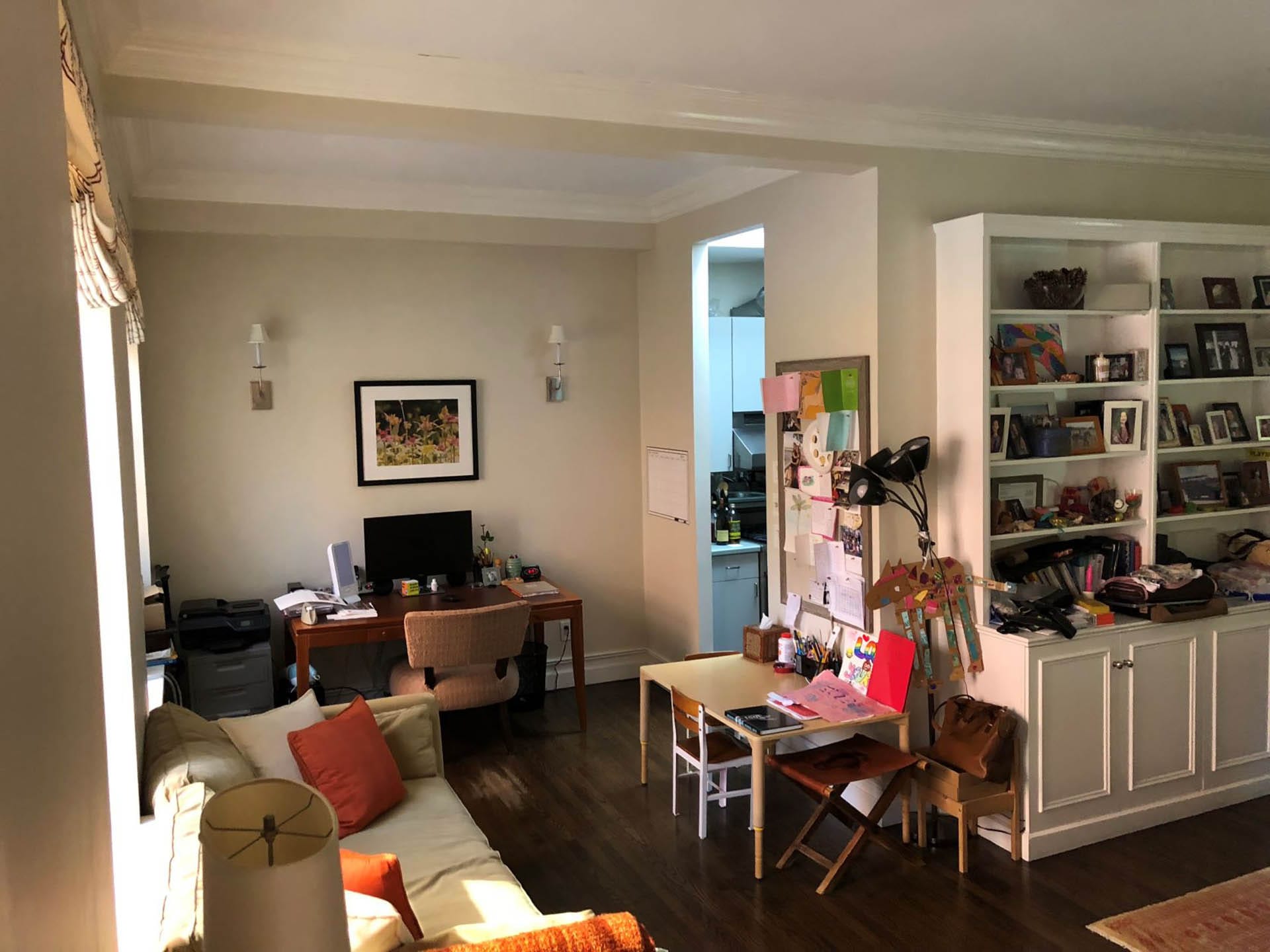 Office space with tan walls leading into a small, closed off kitchen in a Brooklyn Heights apartment