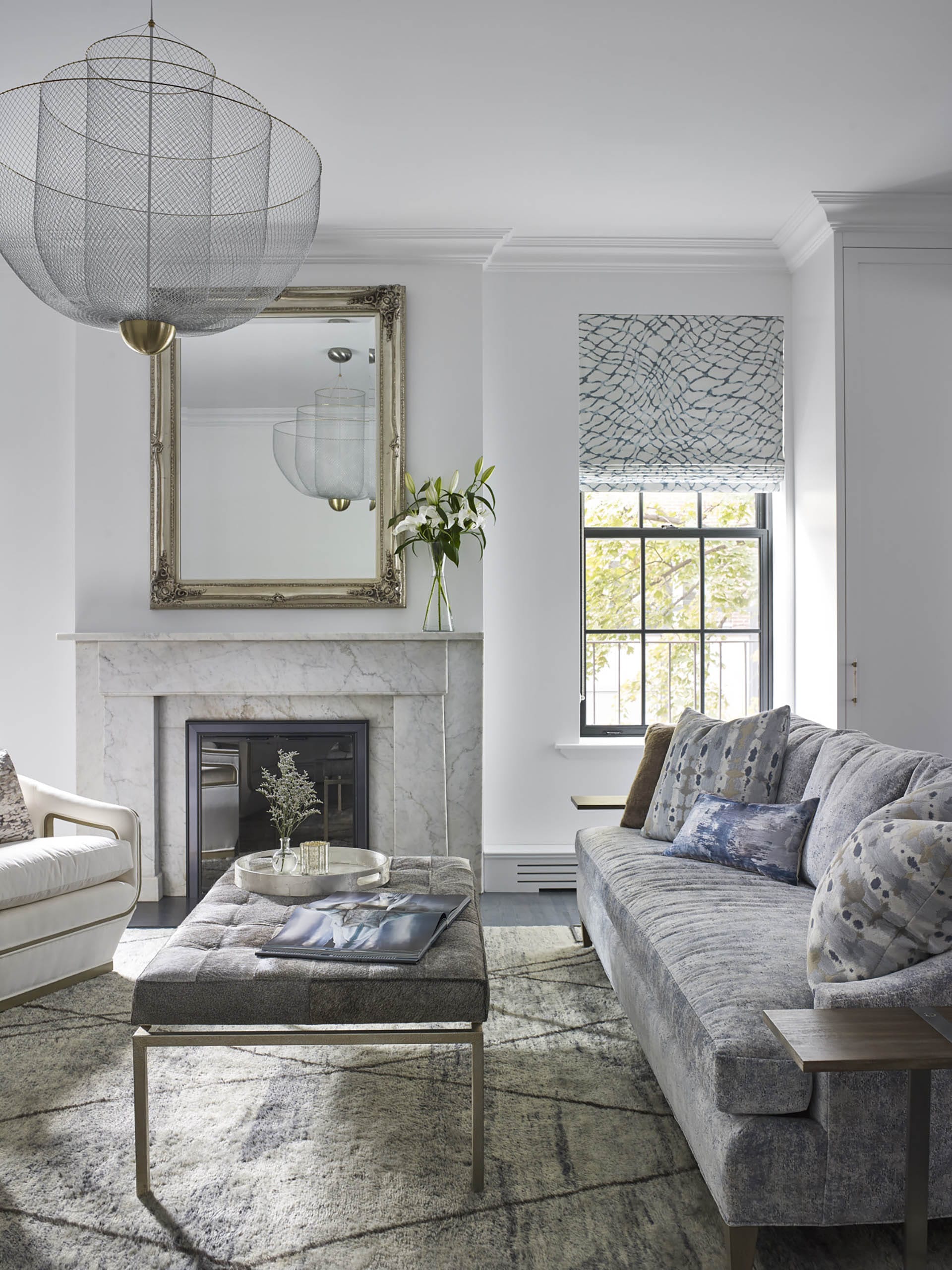 Living room with a textured couch and carpet, mesh chandelier, and marble fireplace