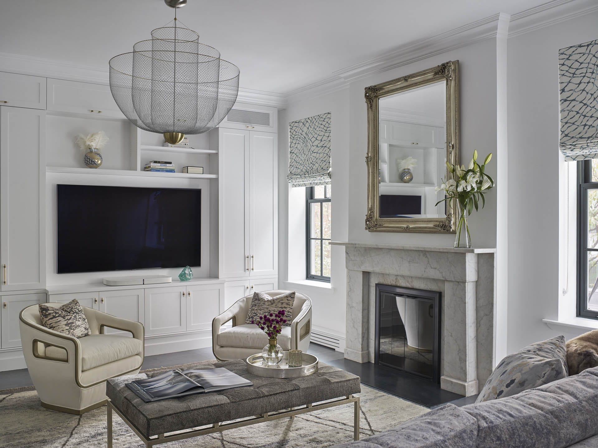 Living room with a textured couch and carpet, mesh chandelier, and marble fireplace