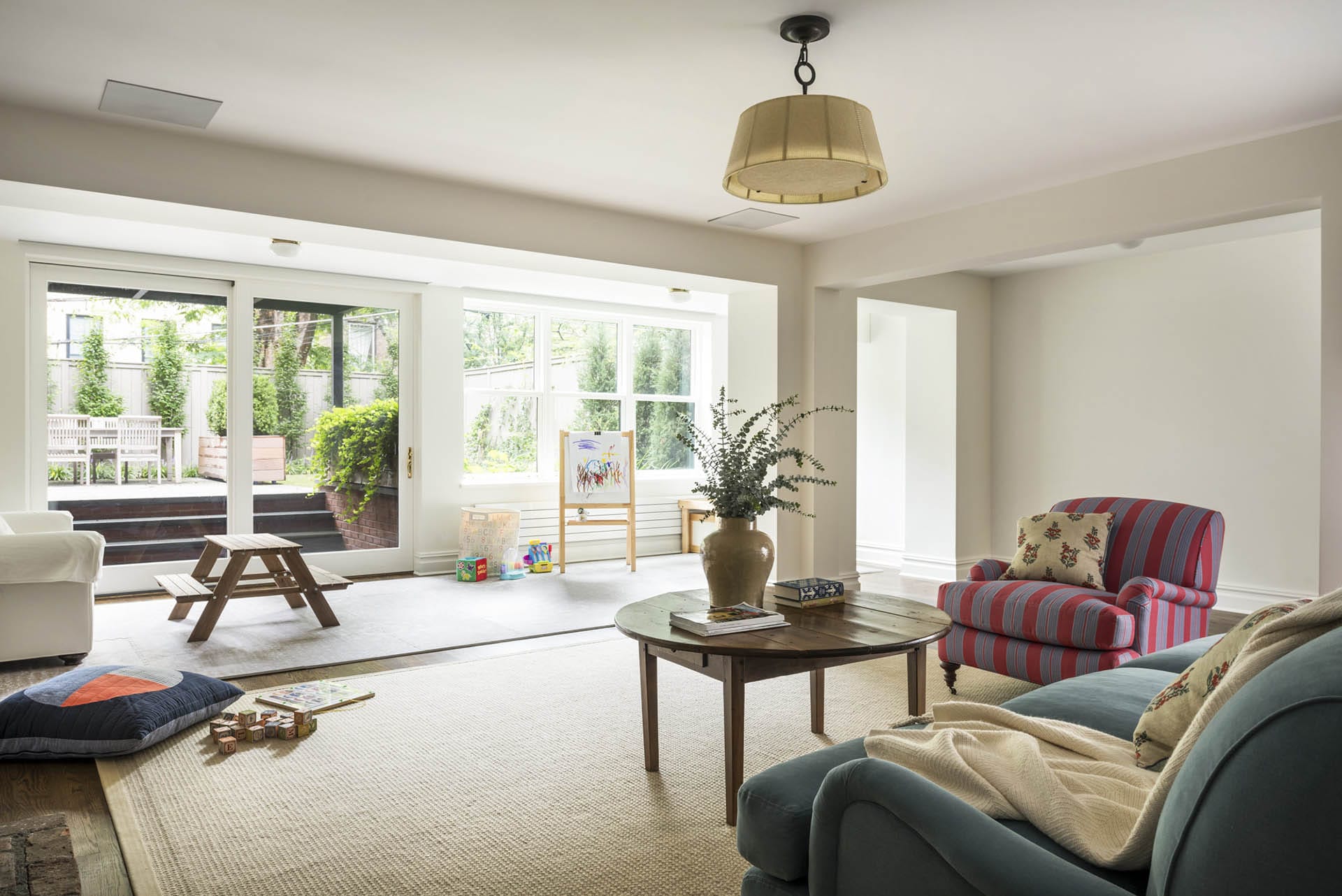 Garden level play room and entertainment space with floor-to-ceiling sliding glass doors leading to the rear yard.