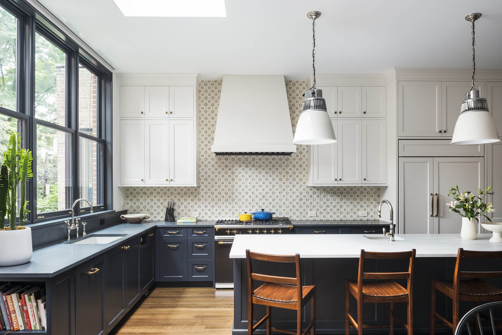 Kitchen with patterned backsplash and blue-painted island and lower cabinets.