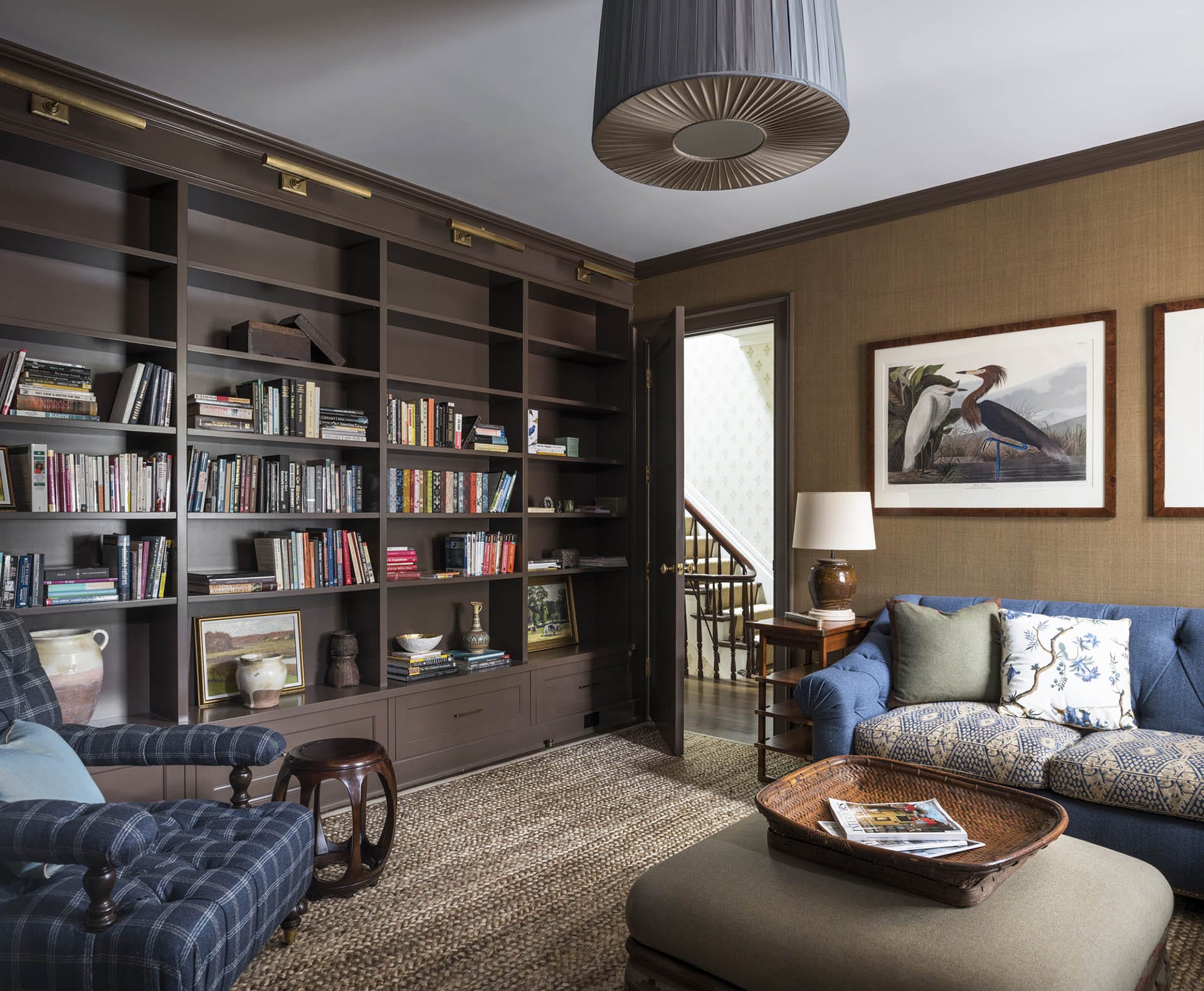 Living room with a wall of built-in bookshelves, blue plaid armchair, and blue couch.