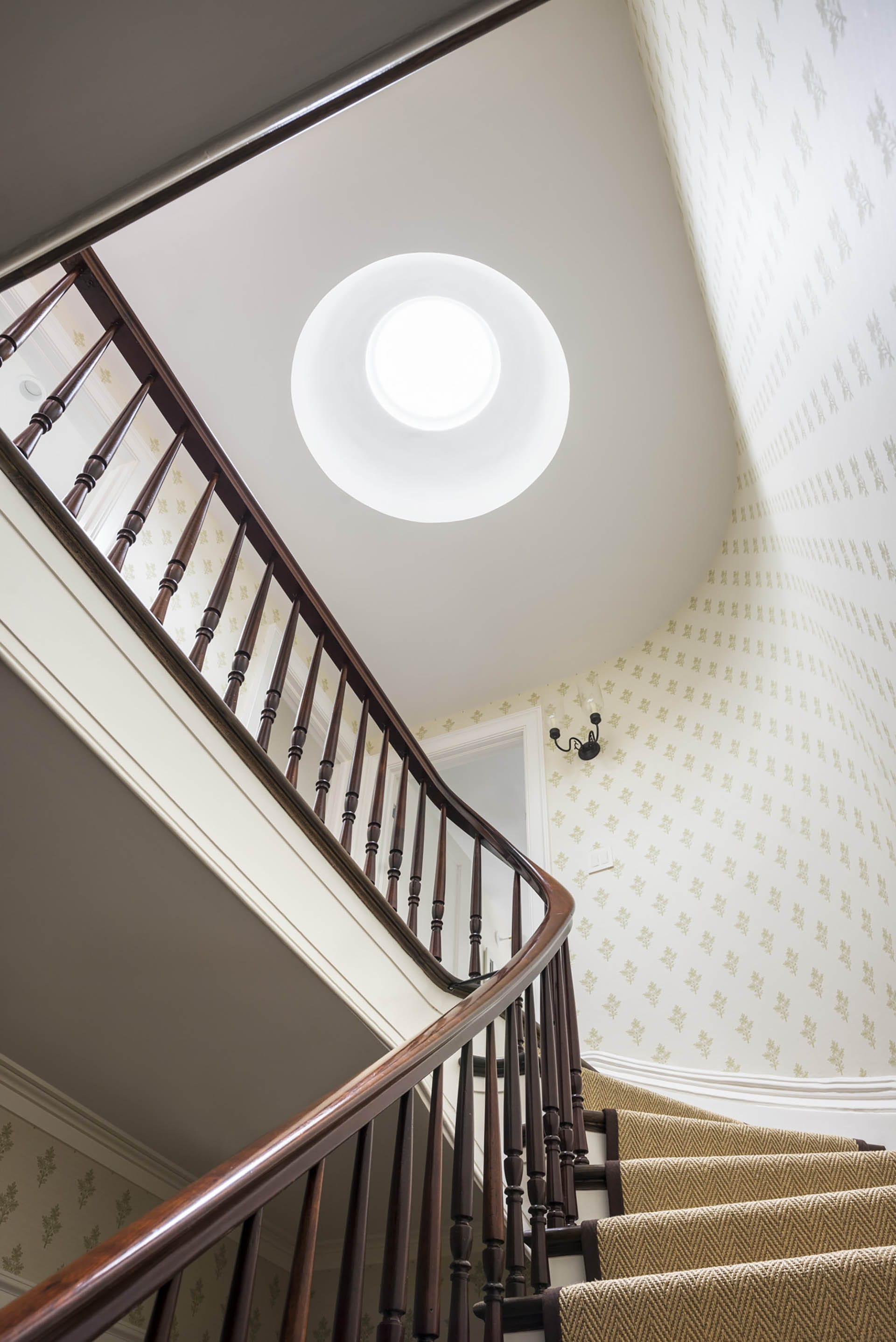 Circular skylight above the main staircase in a Brooklyn Heights home, with wallpaper in the stair hallway.