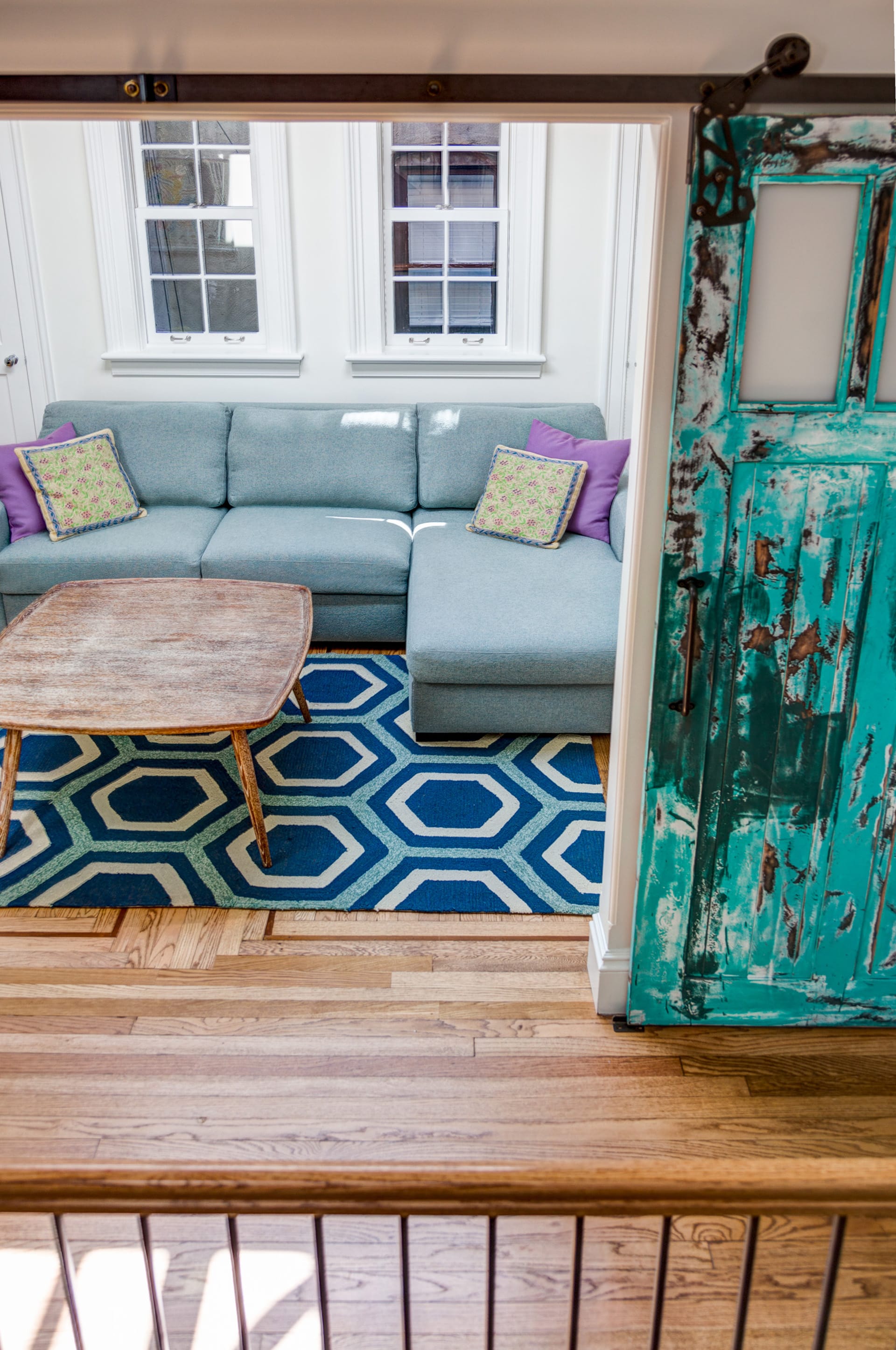 Den with a blue-grey couch and a teal, aged barn door