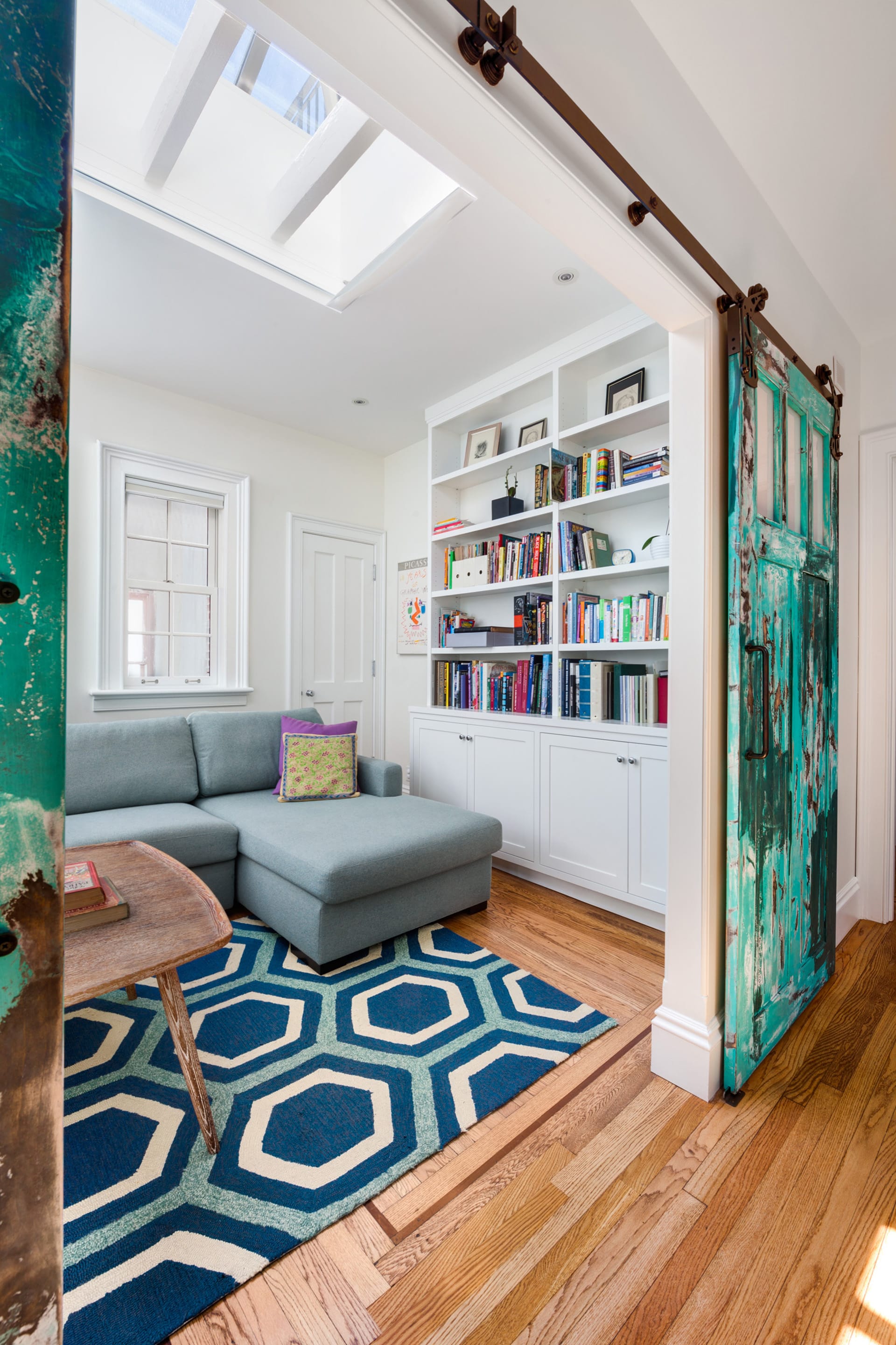 Den with a large skylight, built-in bookshelves, and aged teal barn doors