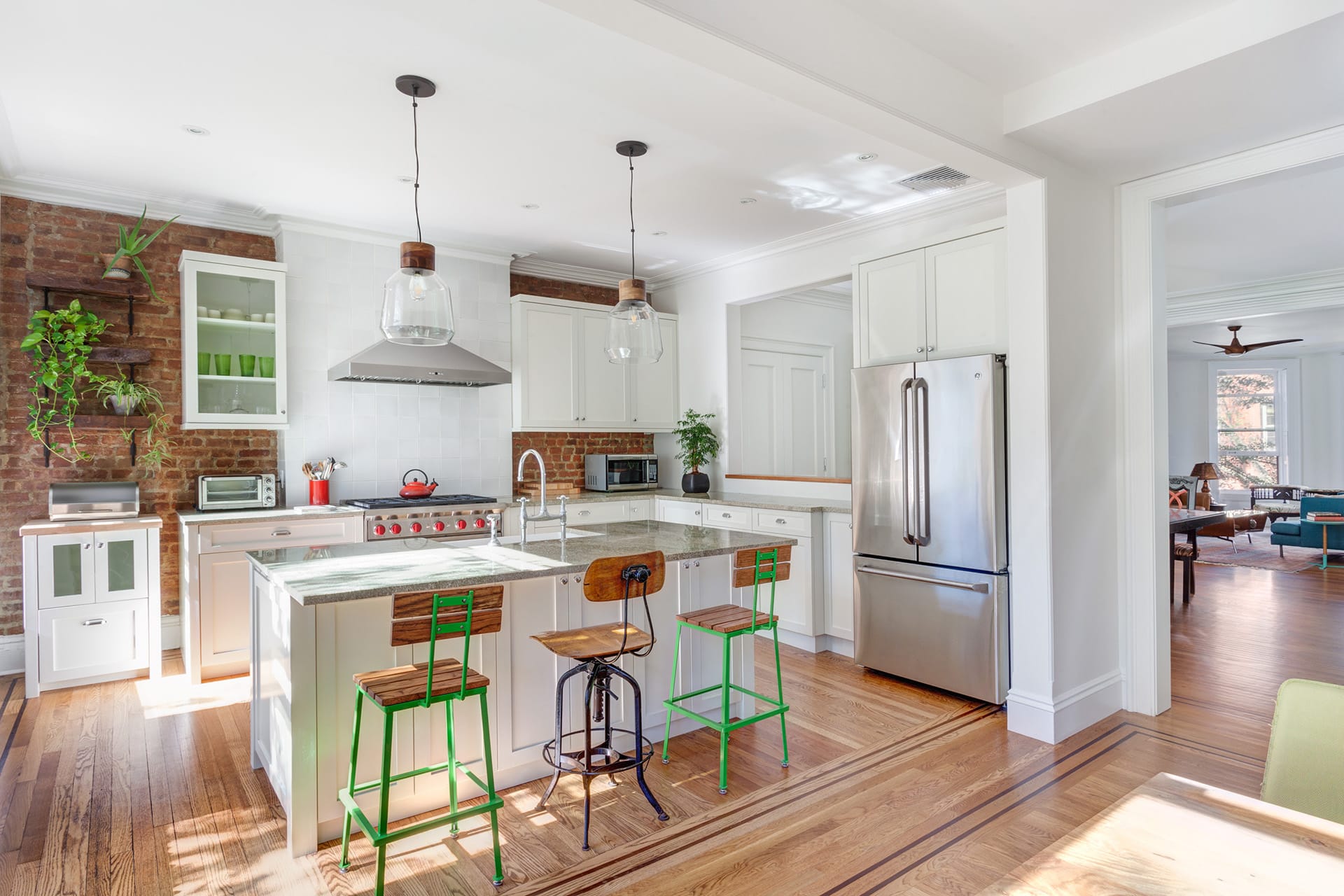 Kitchen with an exposed brick wall, wood floors, and white millwork