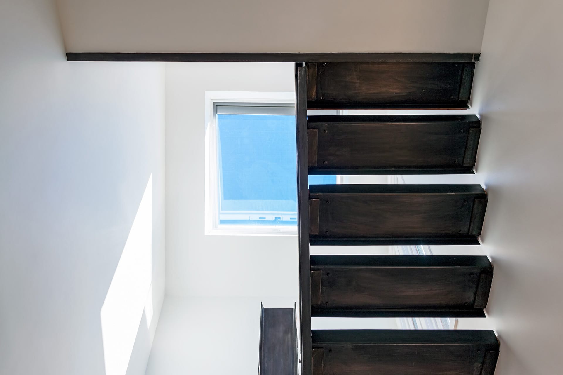Open riser, open stringer metal staircase below a skylight