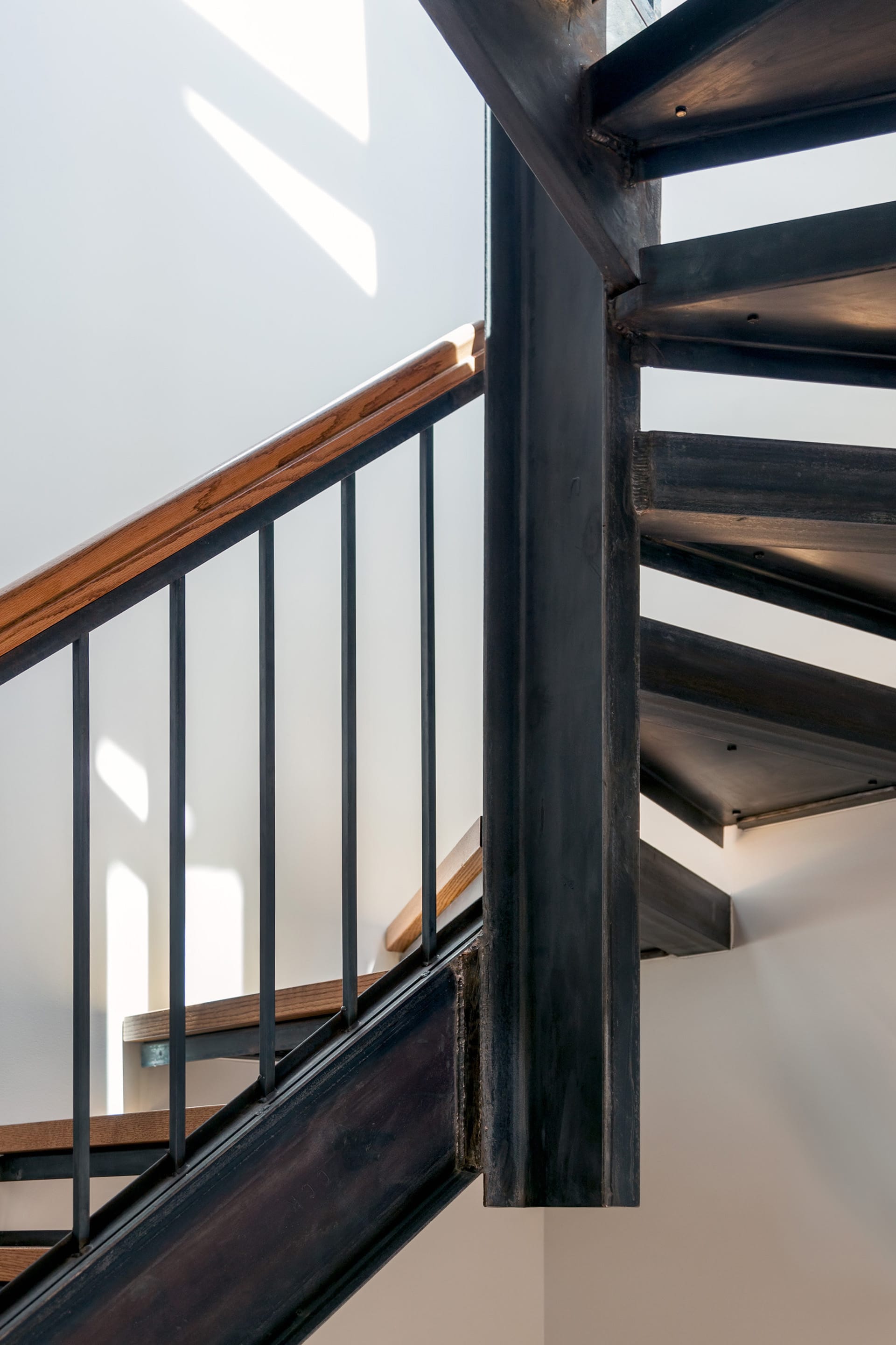 Open stringer, open riser staircase with wood handrail and treads.