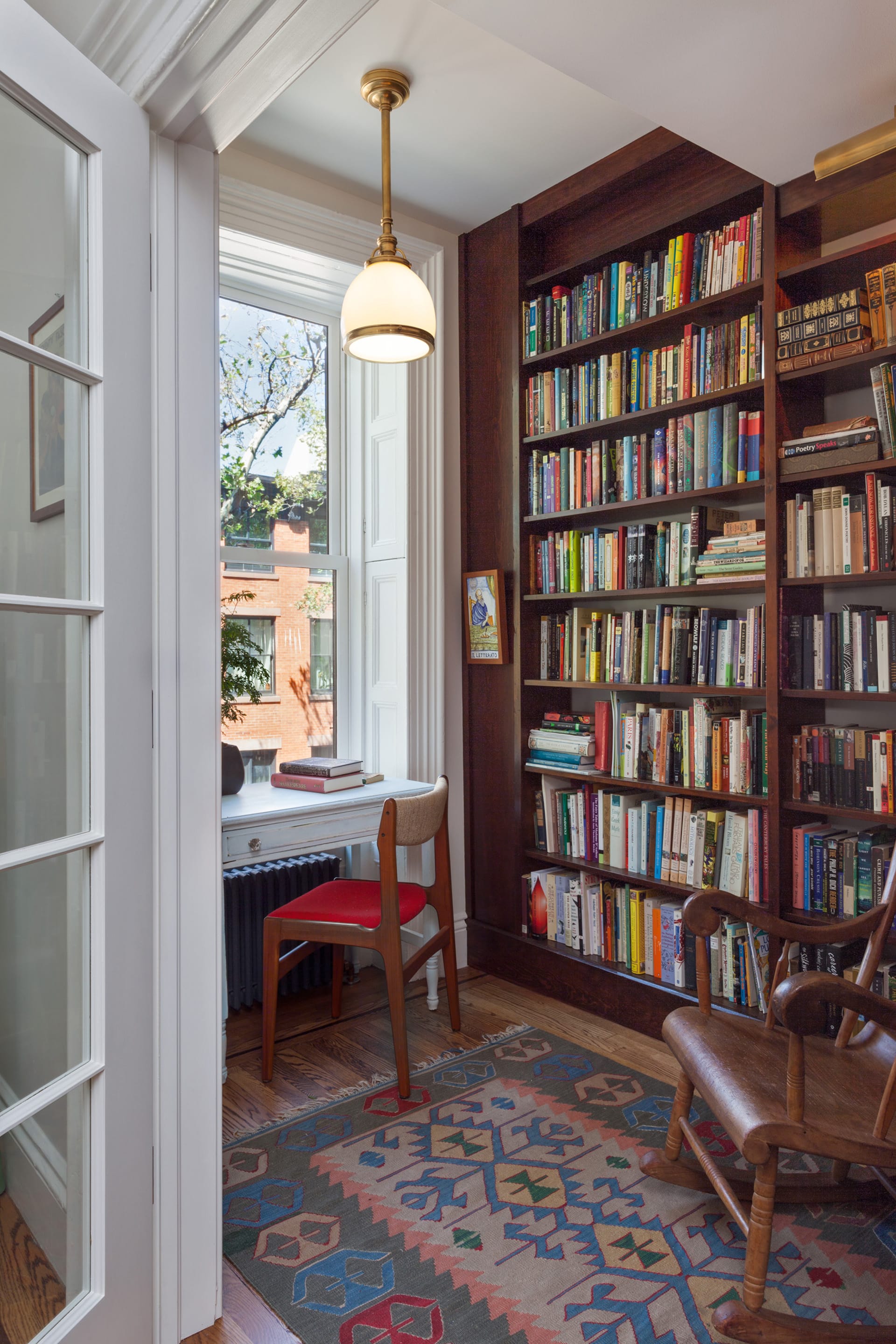 Study with built-in bookshelves and a desk in front of a large window.