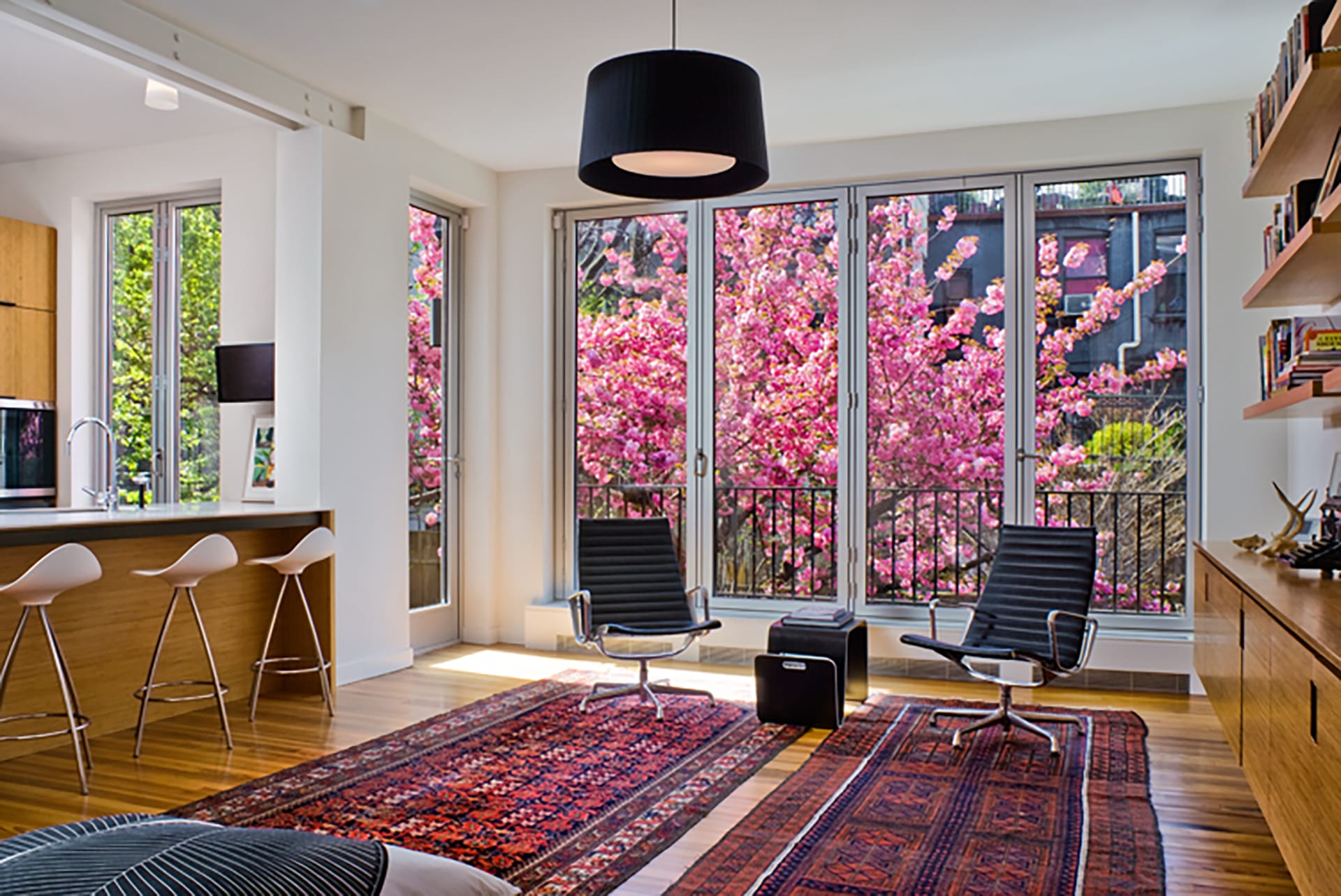 Living room with two matching oriental rugs, black pendant light, and four NanaWall glass doors leading out to the back yard.