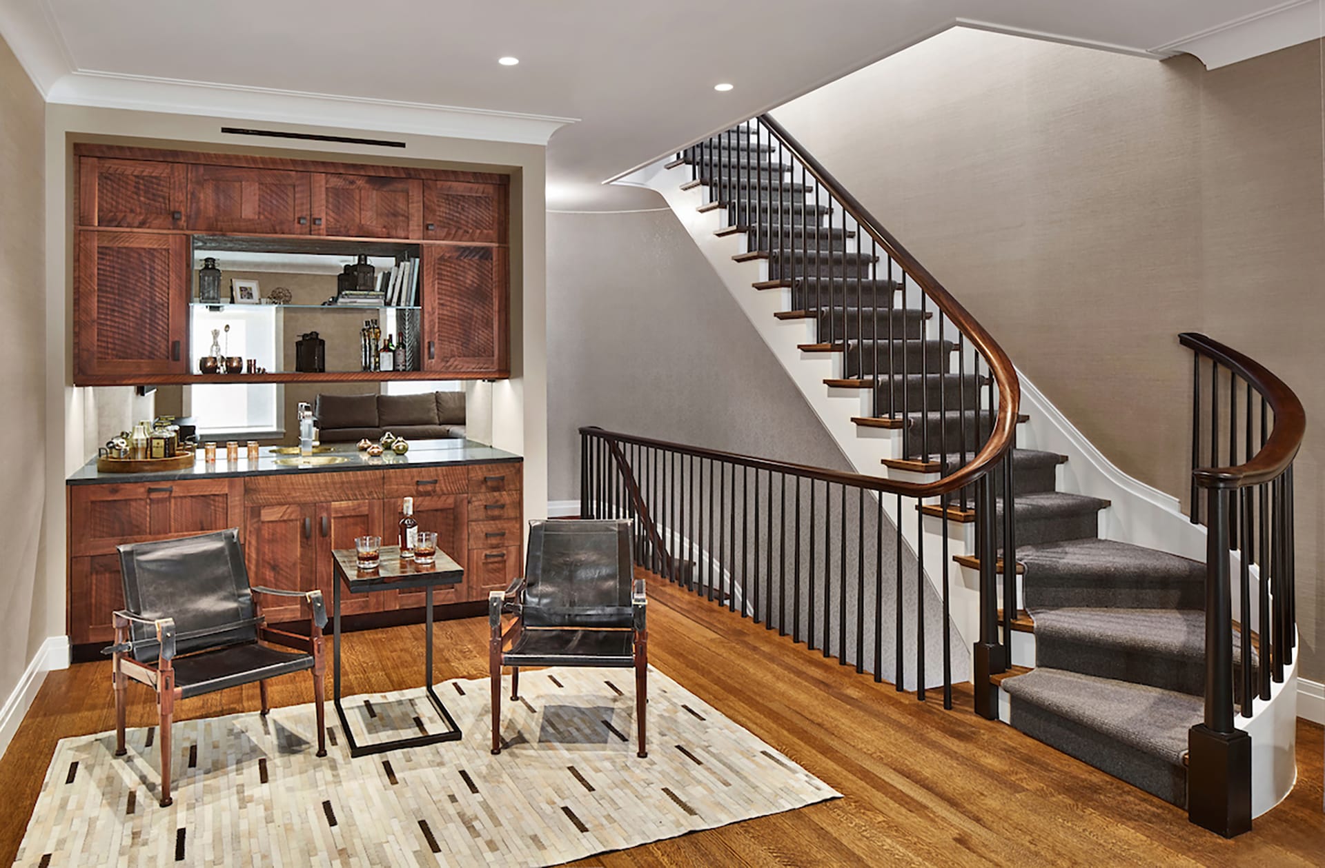 Recreation room with a dry bar next to an open staircase with a grey stair runner