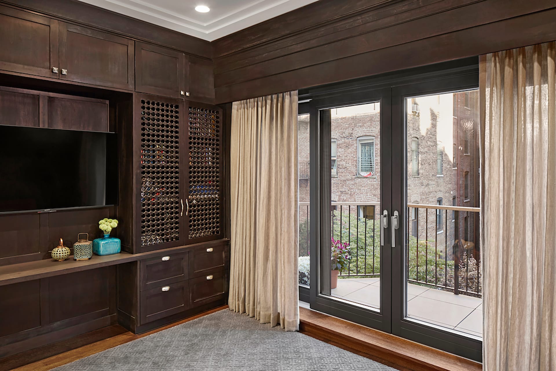 Library with dark wood millwork and French doors leading out to a balcony.