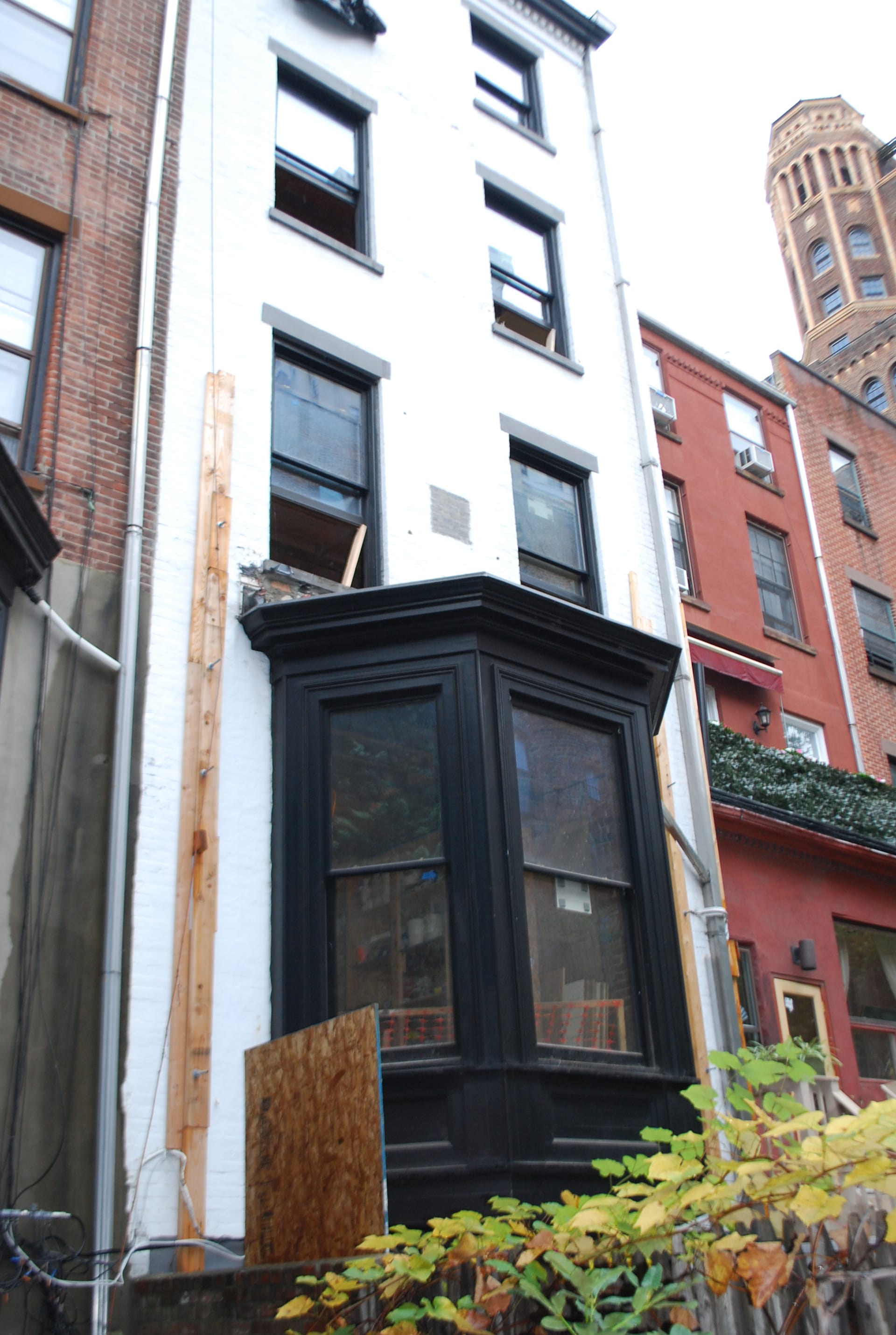 White painted brick rear exterior with a one-story black bay window before our renovation.