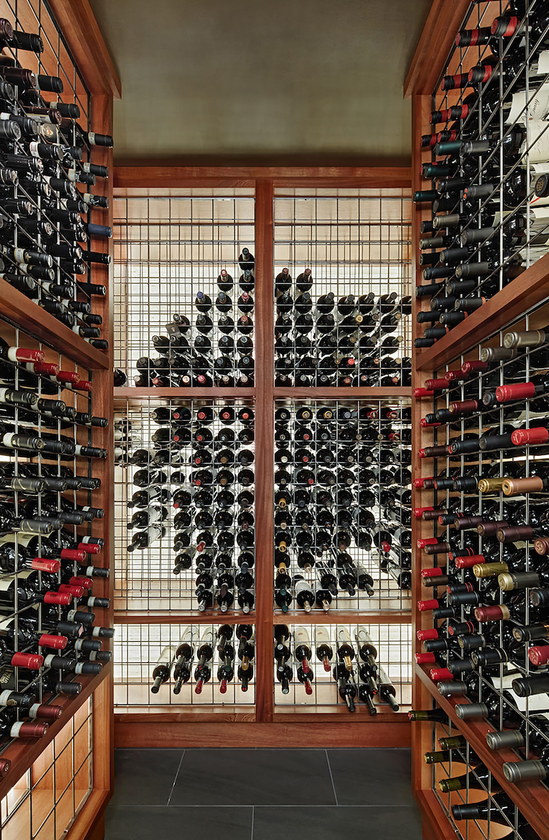Wine cellar with green ceiling, wood framed storage, and a wire system to store bottles of wine.