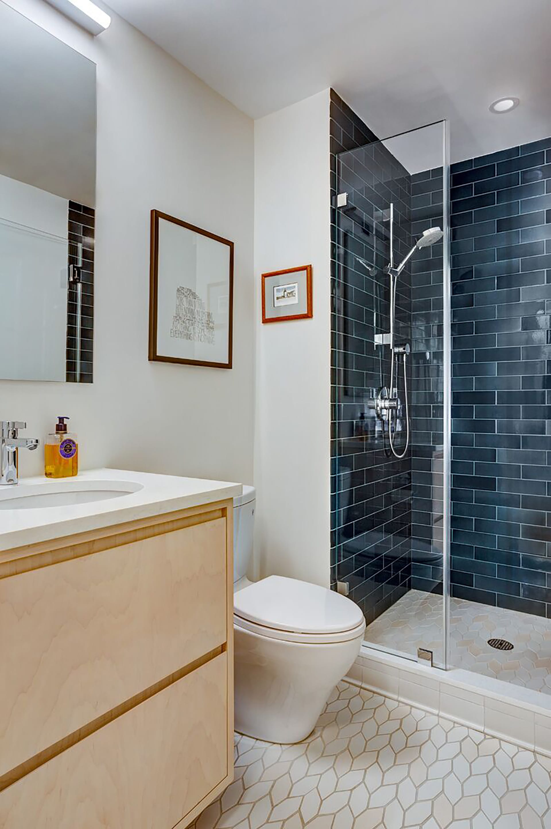 Brooklyn heights bathroom with dark teal subway tiles in the shower stall, white floor tiles, and a light wood vanity.