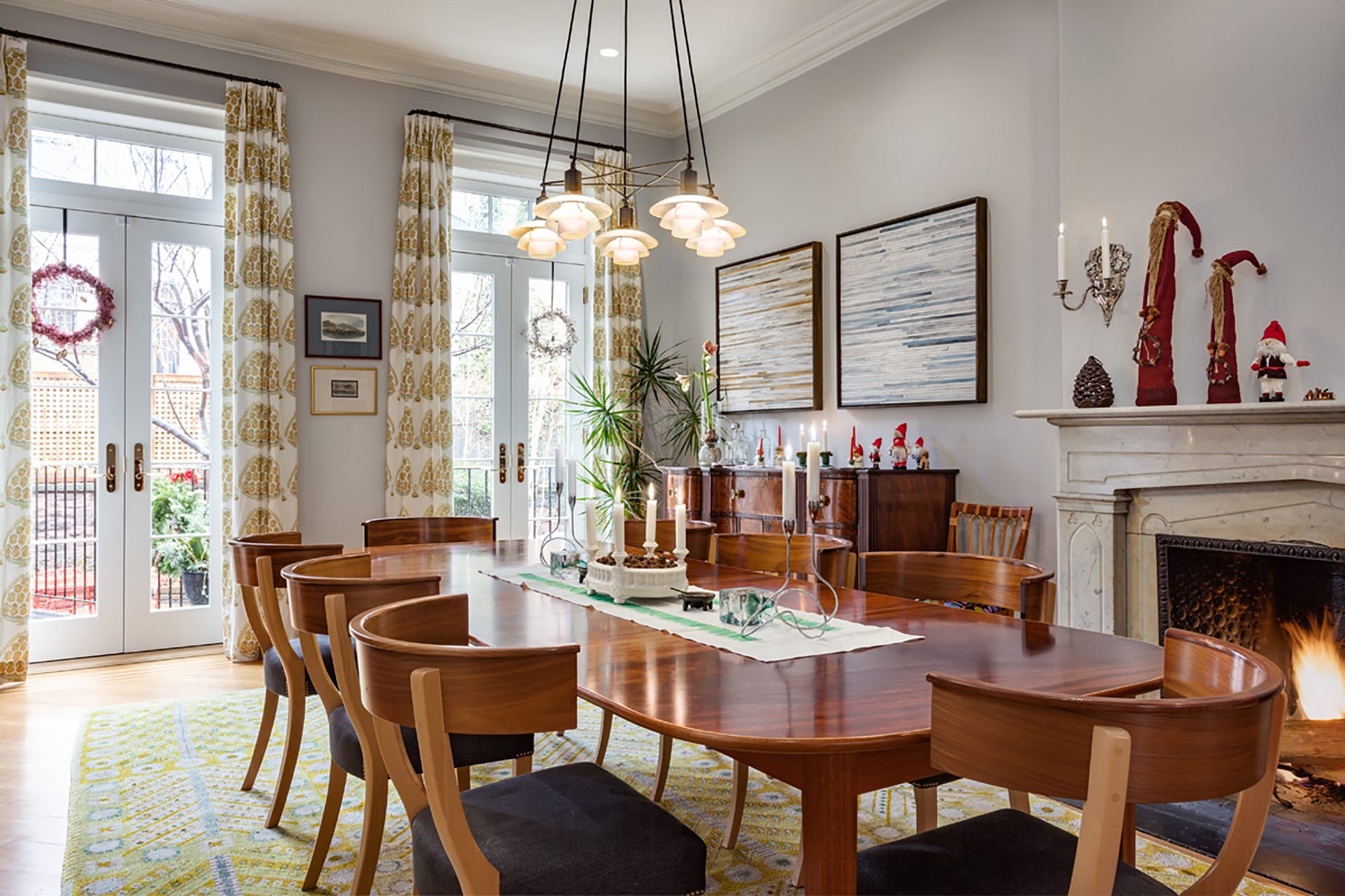 Dining room with two set of French doors leading to the rear yard, light grey walls, and wood dining table and chairs.