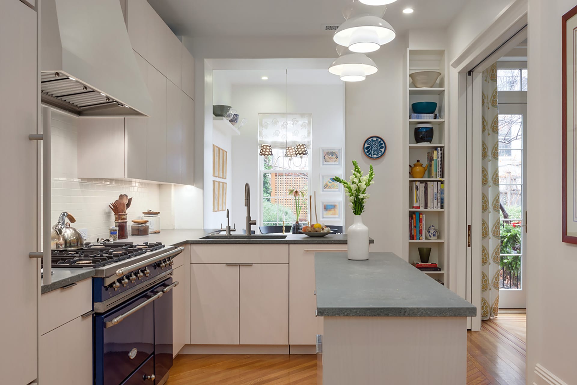 Upgraded, double-loaded kitchen with a small island, blue countertops, and interesting semi-flush light fixtures in a Brooklyn Heights home