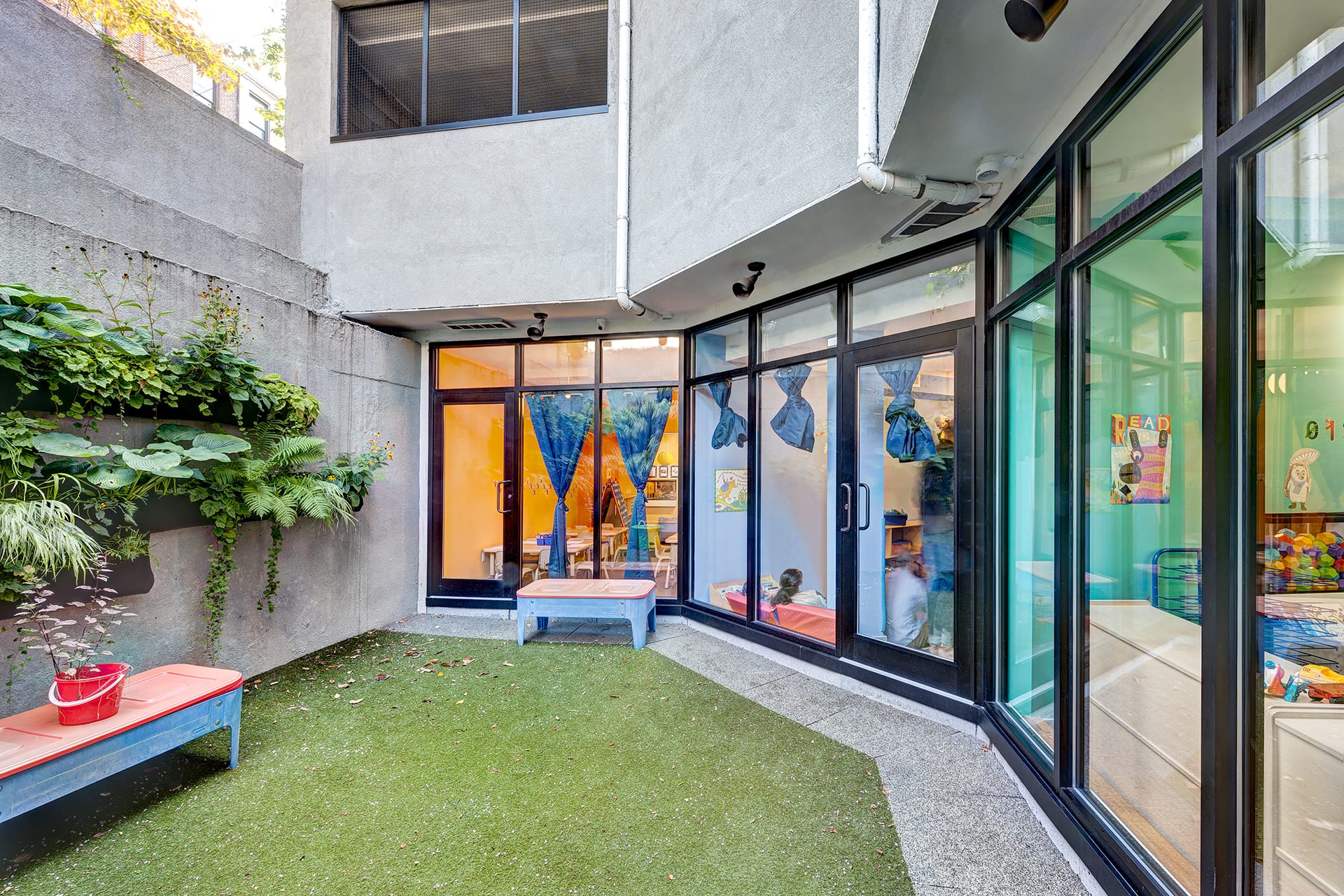 Rear yard with benches, planters built into the cement wall, and access to all three classrooms.