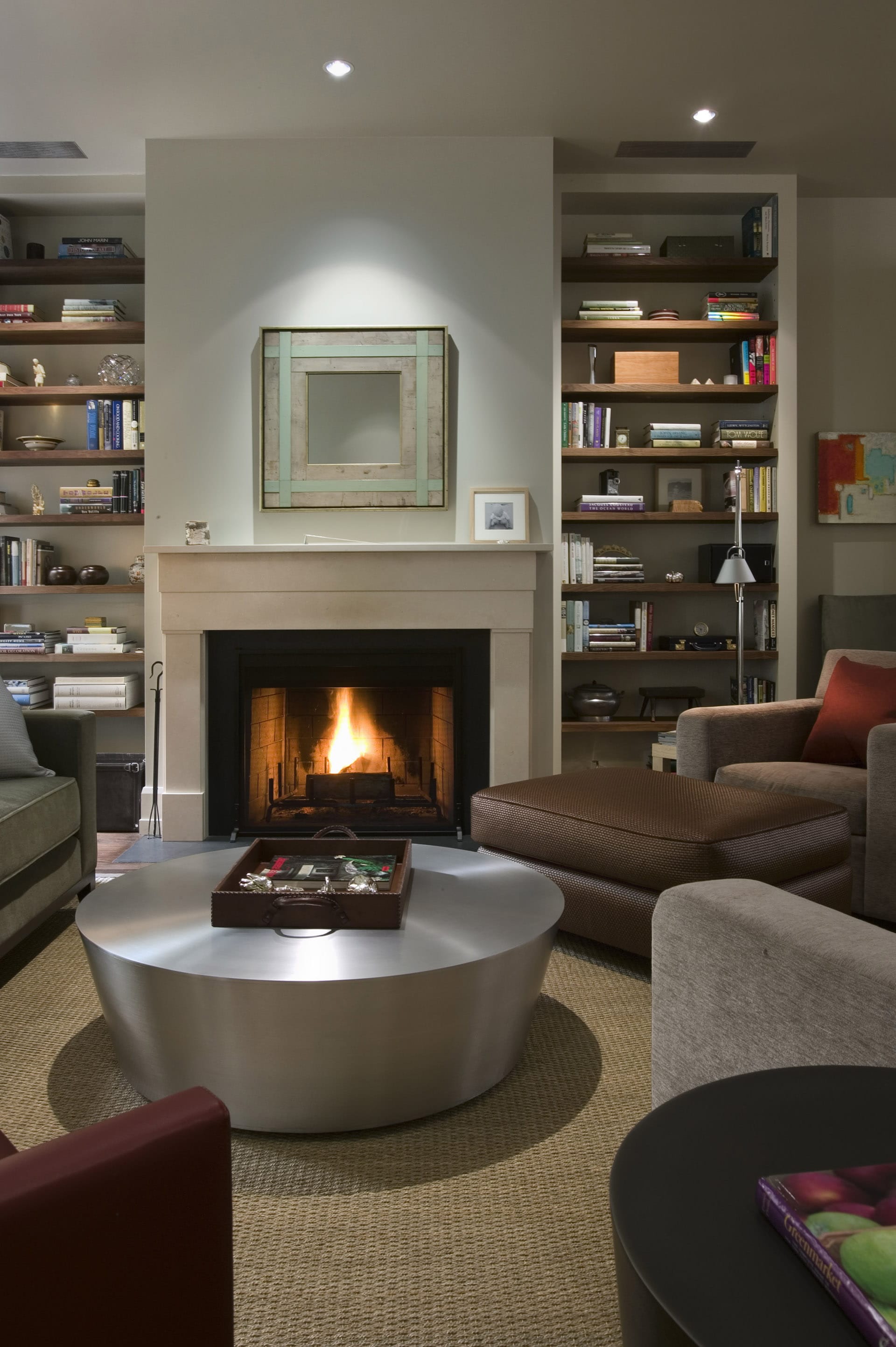 Living room with a fireplace and round stainless steel coffee table.