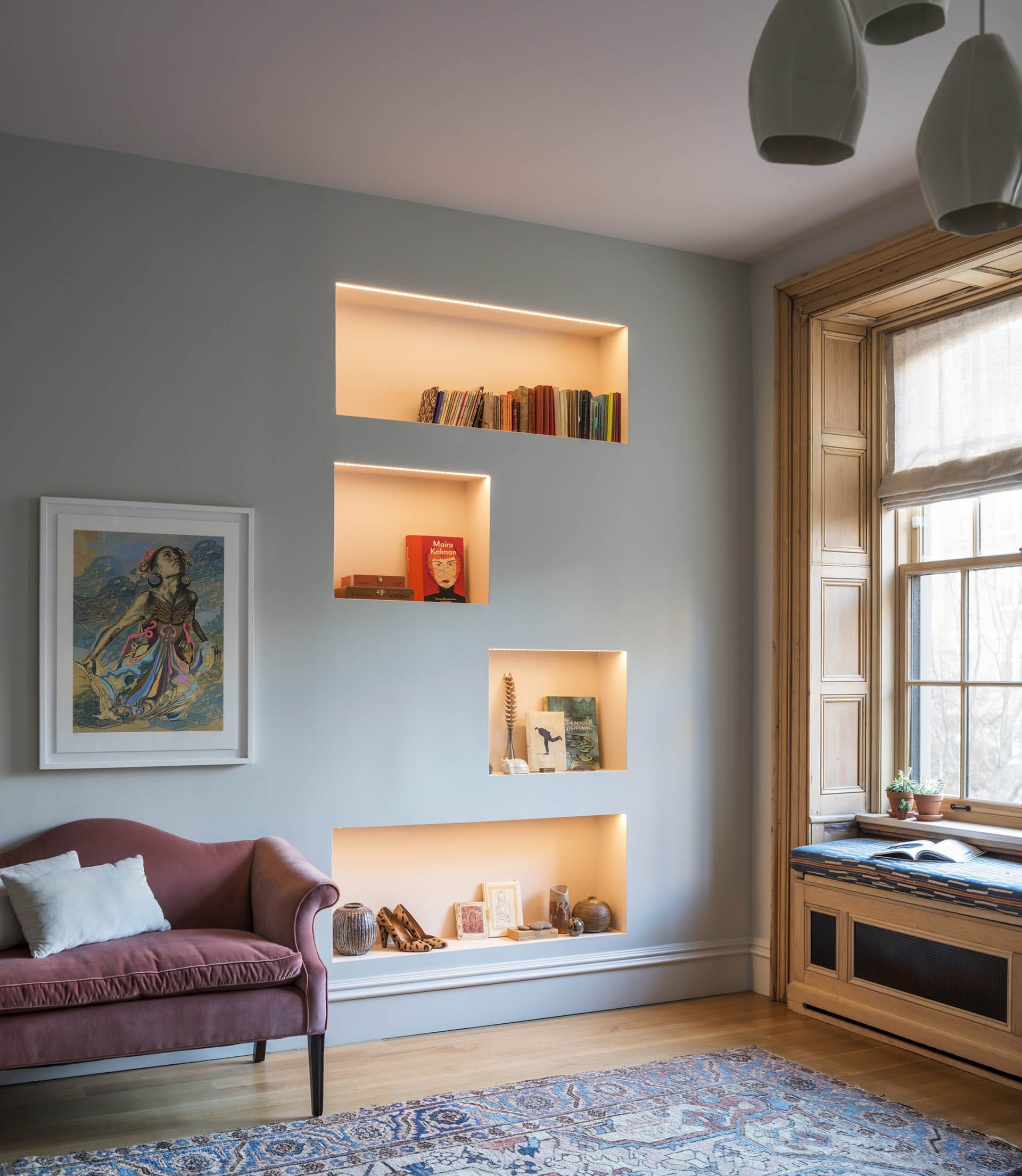 Living room with four backlit built-in cubbies next to a bumped out window seat.