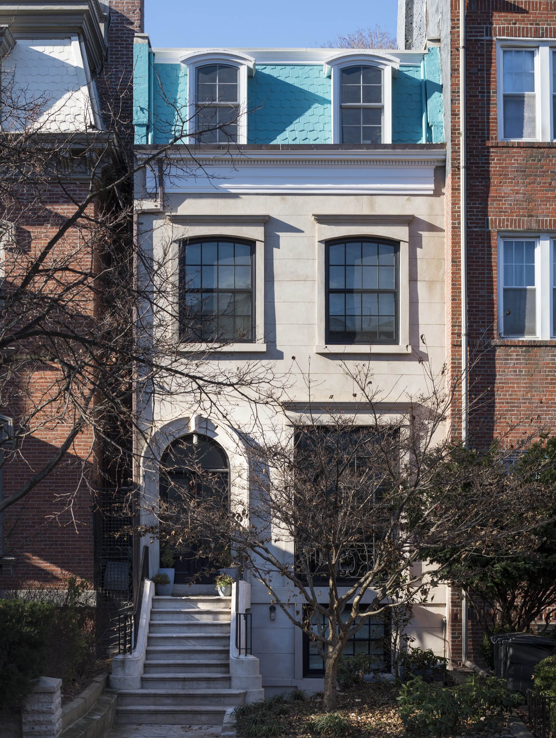 Front façade of a stucco Clinton Hill rowhome with light blue painted shingles.