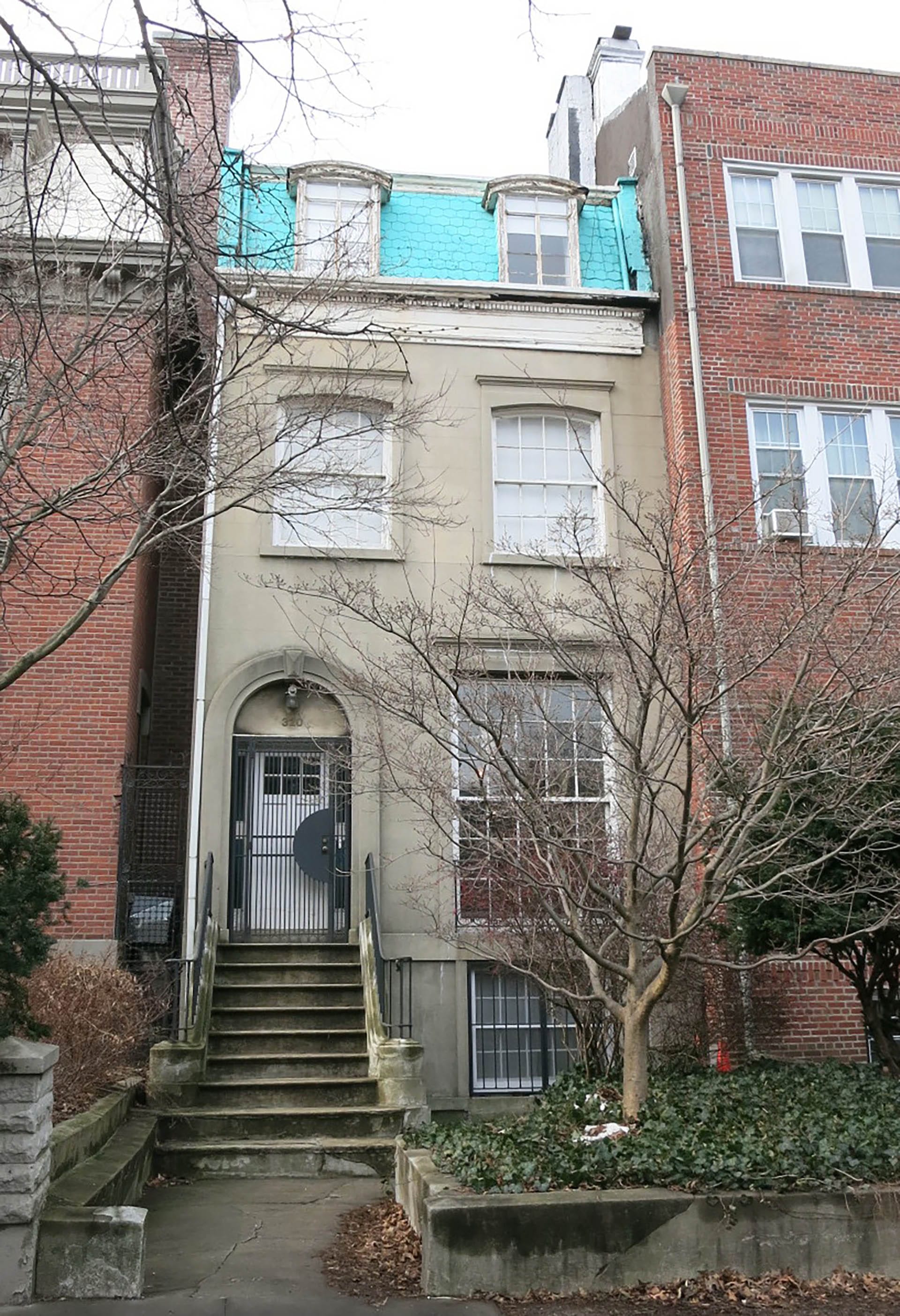 Front façade of a stucco Clinton Hill rowhome with light blue painted shingles before renovation