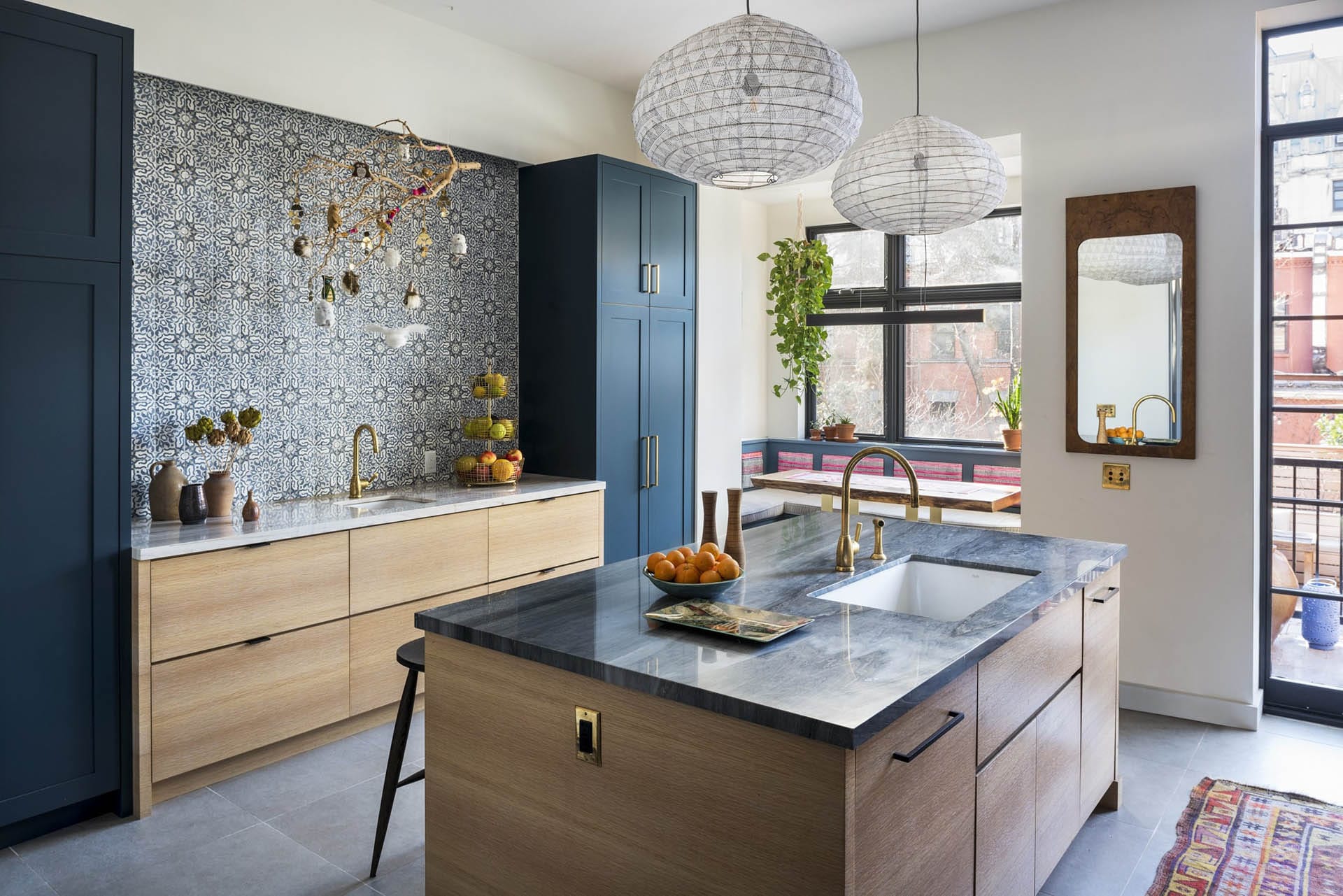 Kitchen with natural wood island, dark teal floor-to-ceiling cabinets, patterned tile backsplash, and marble countertops