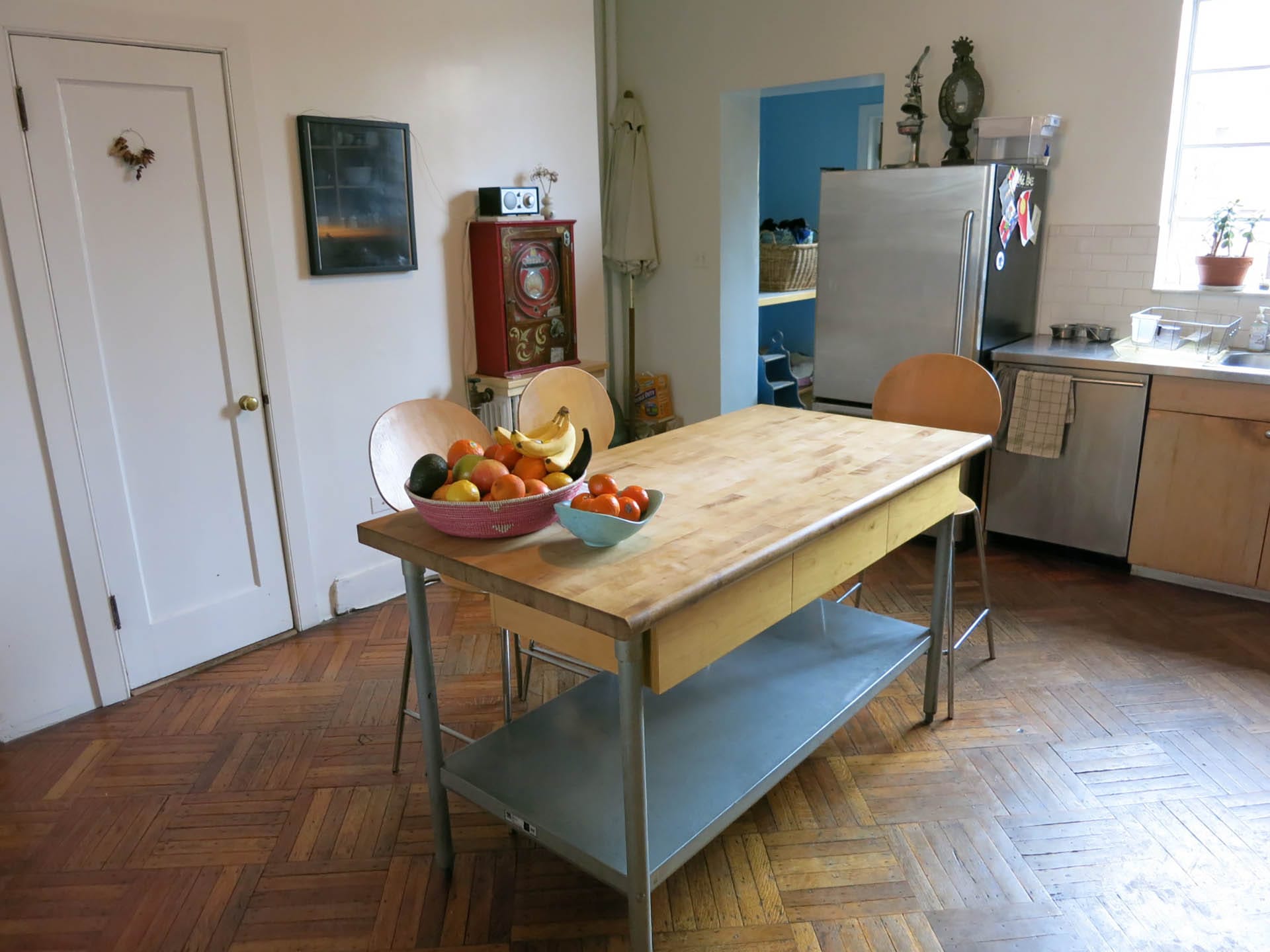 Kitchen before our renovation, with parquet wood floors, a portable island, and stainless steel appliances.