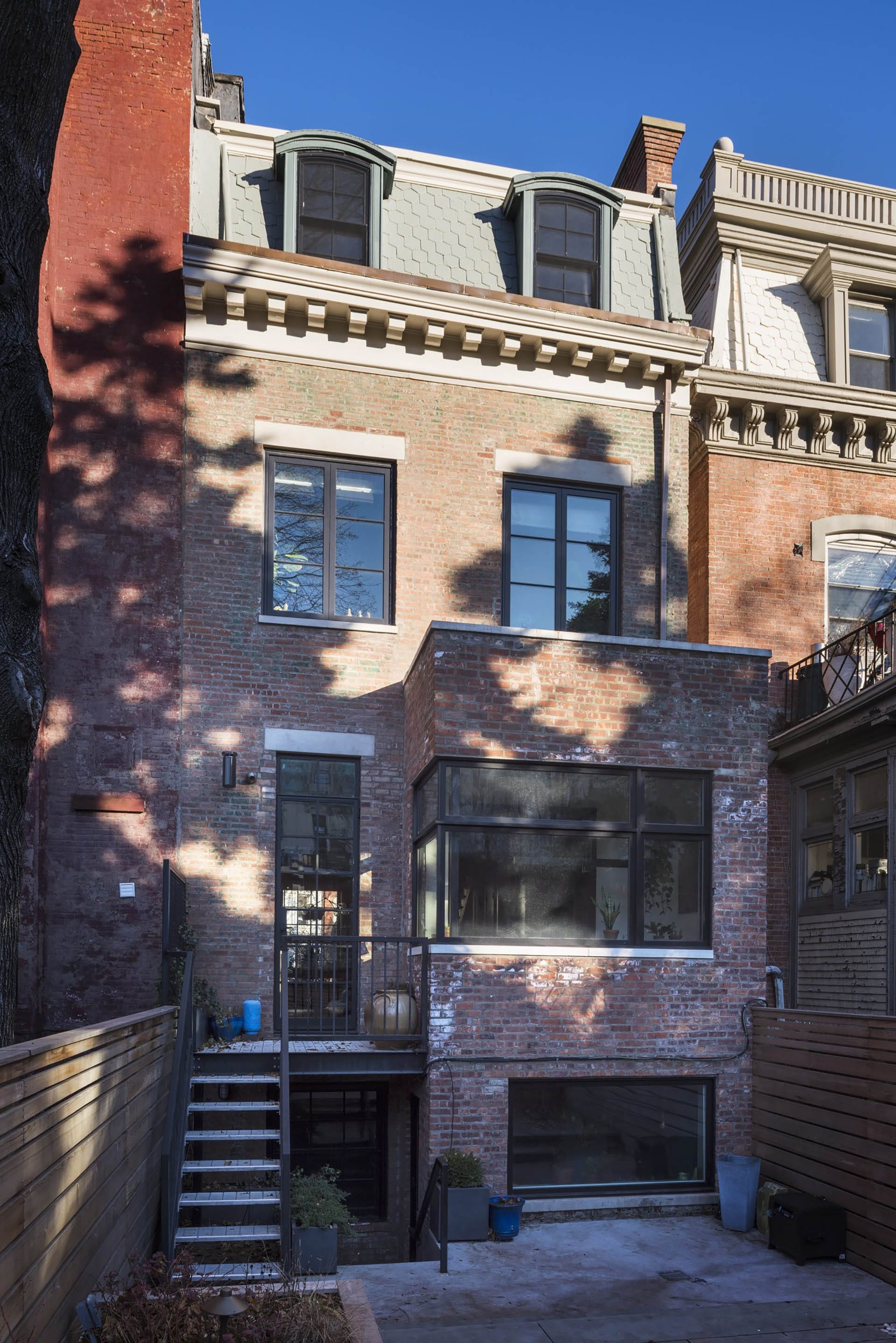 Refurbished brick rear façade of a Clinton Hill rowhome with restored shingles, new windows, and enlarged openings.