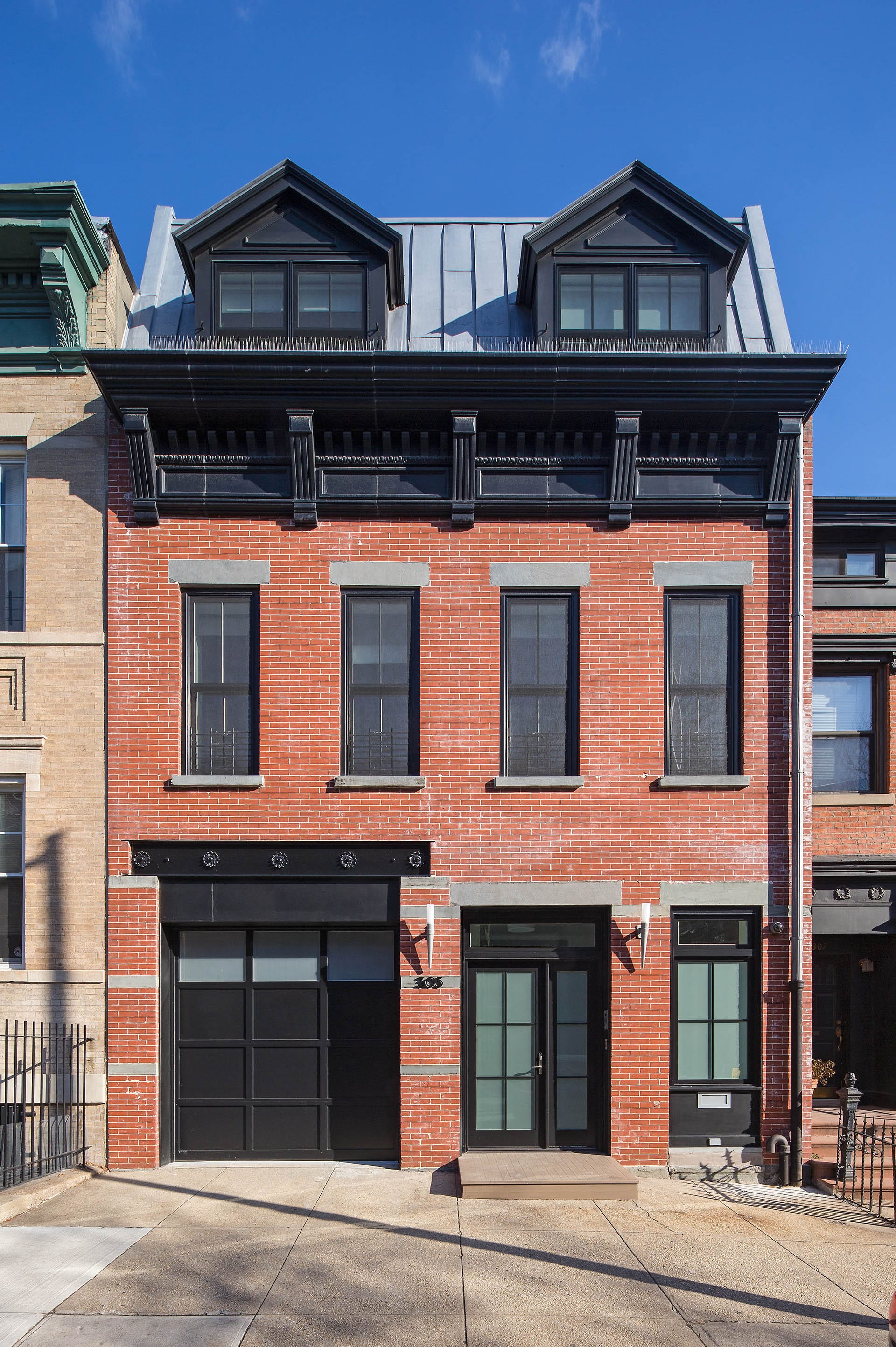 Front facade after our renovation, with black trim, grey lintels, and a full-story addition with dormers.