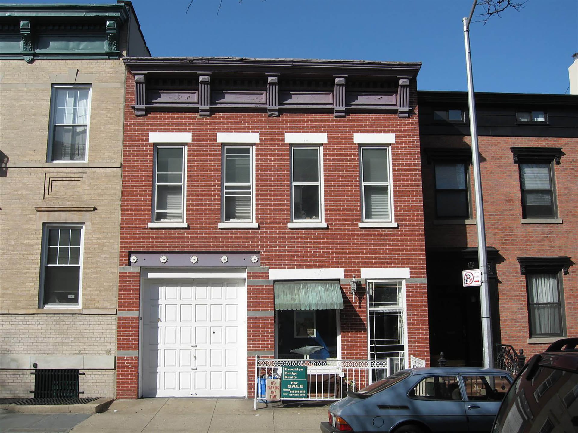 Front facade of a Cobble Hill carriage house with white lintels and garage door, before our renovation