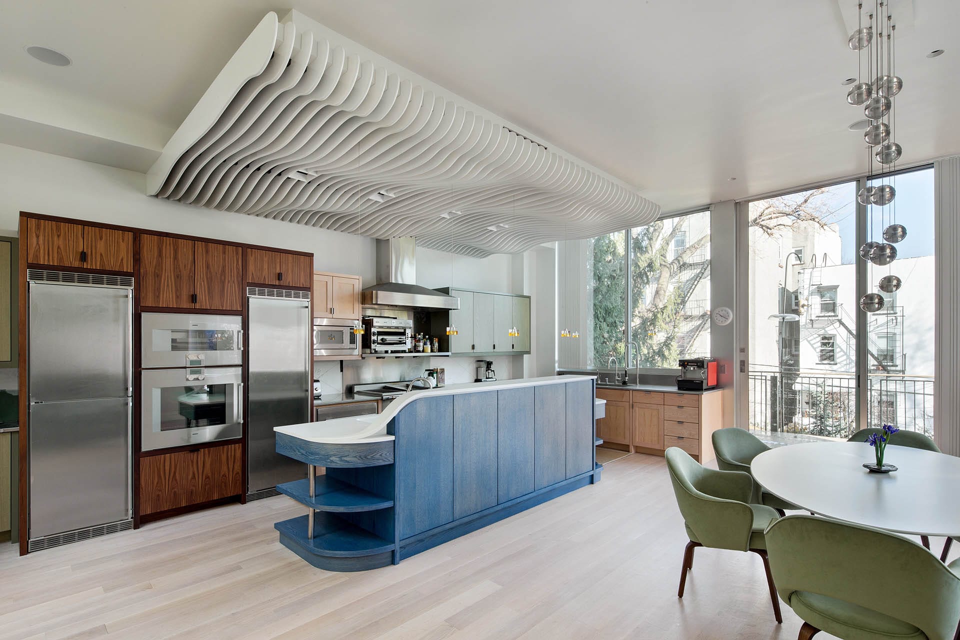 Kitchen with mixed wood cabinetry, a blue wood island, bocce light fixture, and white sculptural element on the ceiling