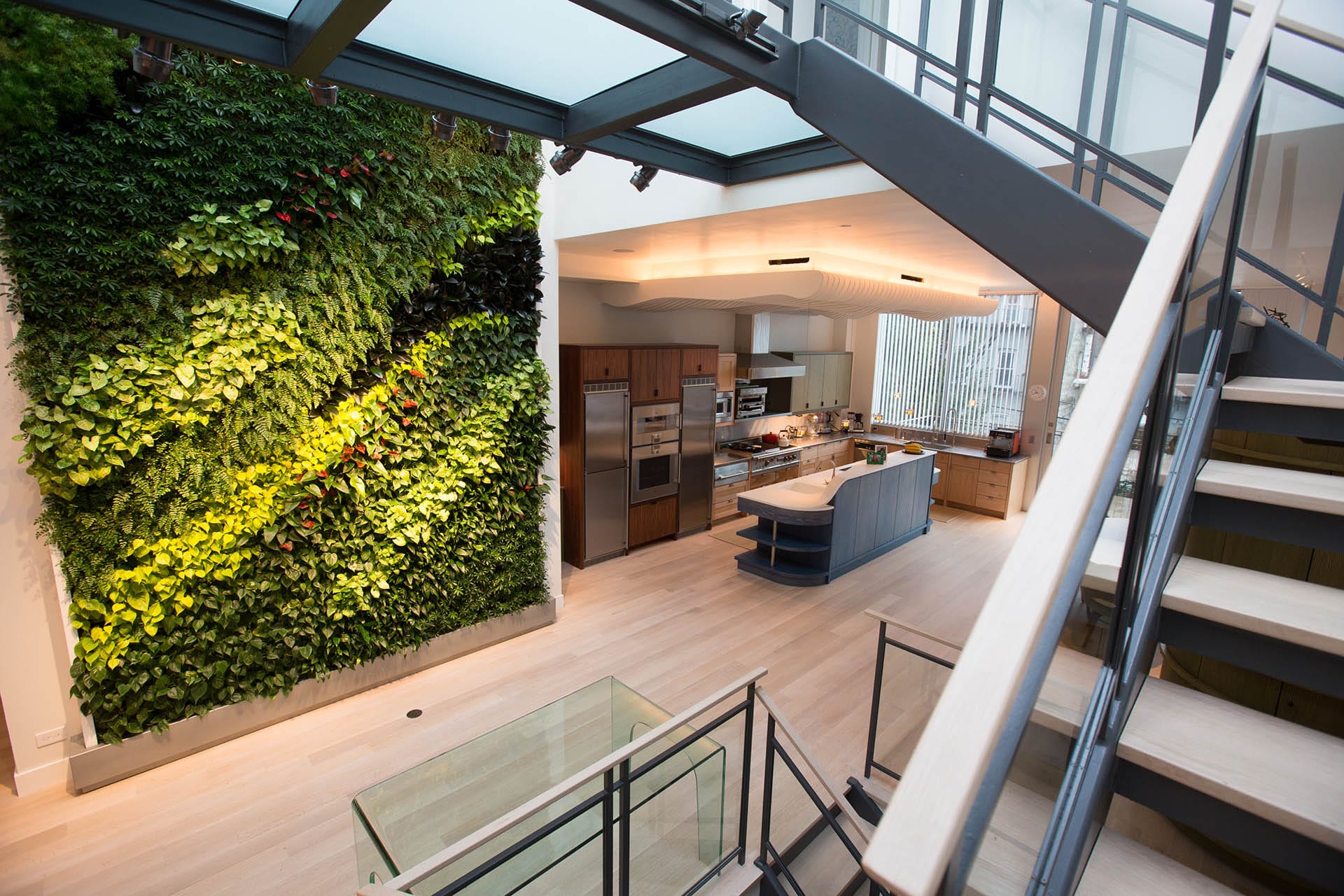Living wall next to an open concept kitchen with a blue island and natural wood cabinetry